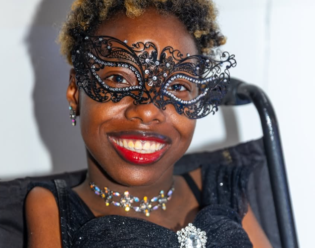 A student in a masquerade mask smiles at prom