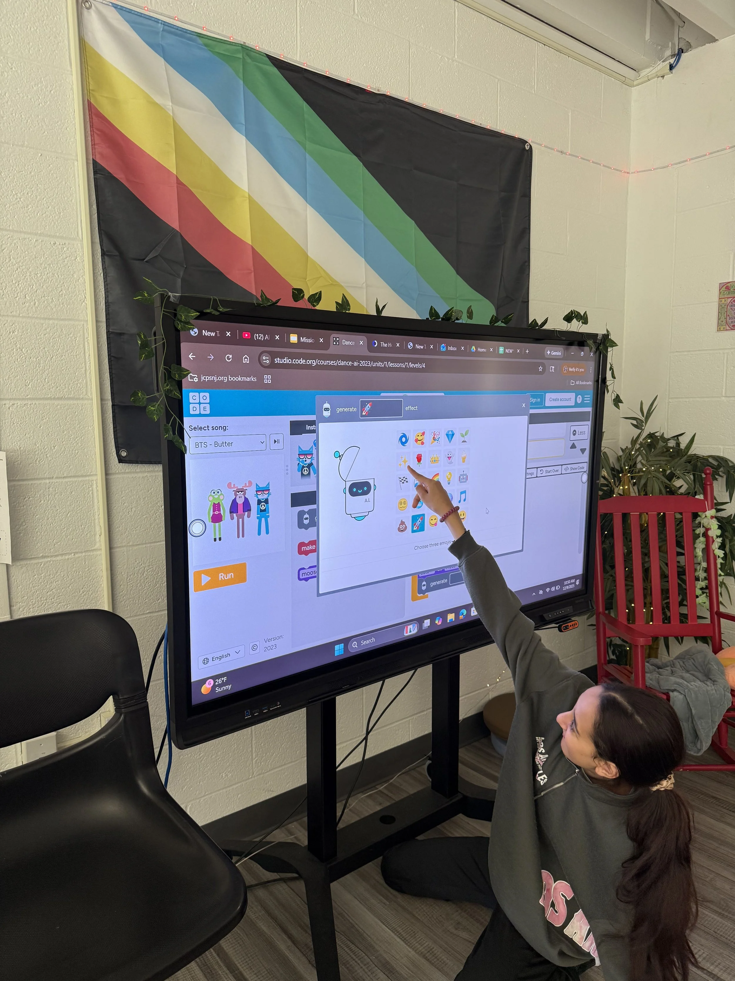 A student points to a coding project on the classroom smartboard