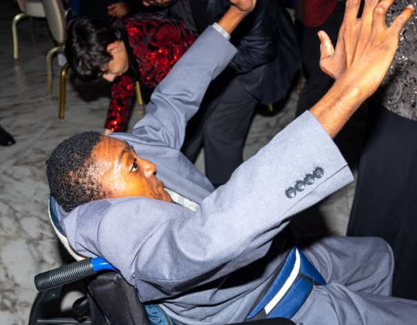 A student throws his arms up on the prom dance floor