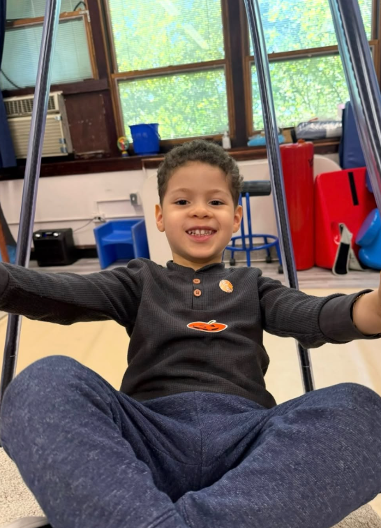 A student enjoys the swing in the sensory room