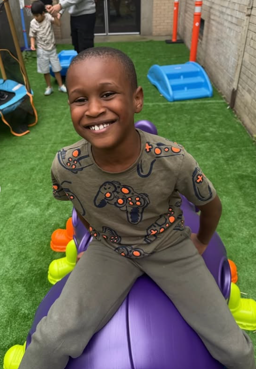 A young student balances on a therapy ball, grinning
