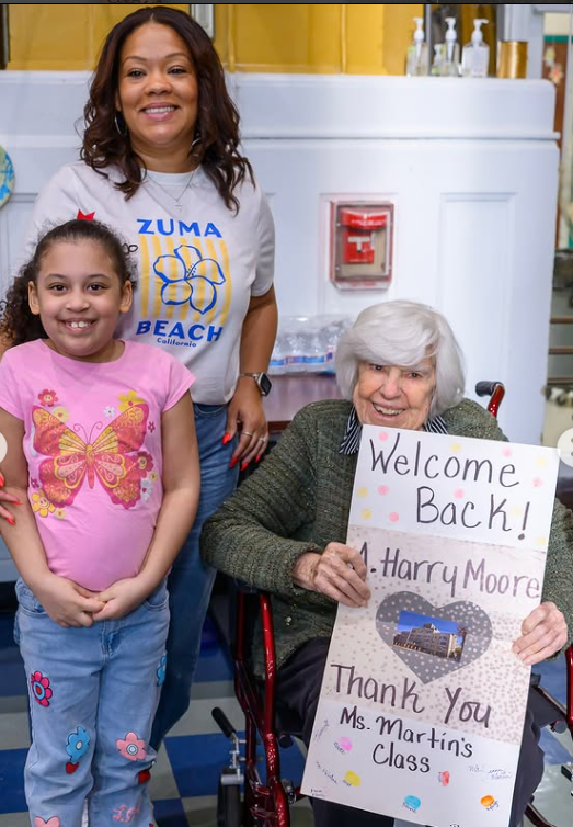 A student and teacher hold a Welcome Back sign on the first day