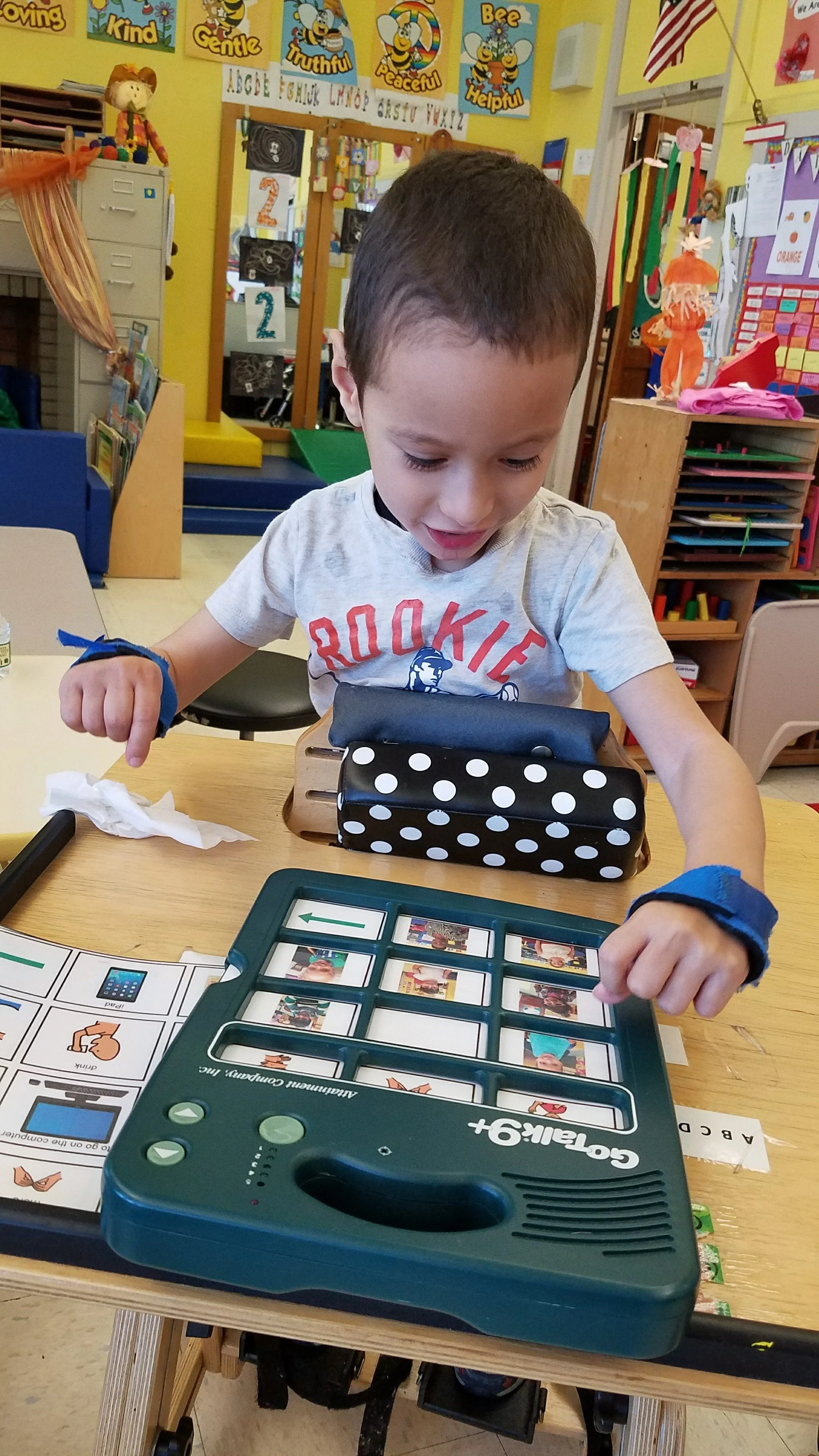 A student uses a low-tech communication book with a teacher