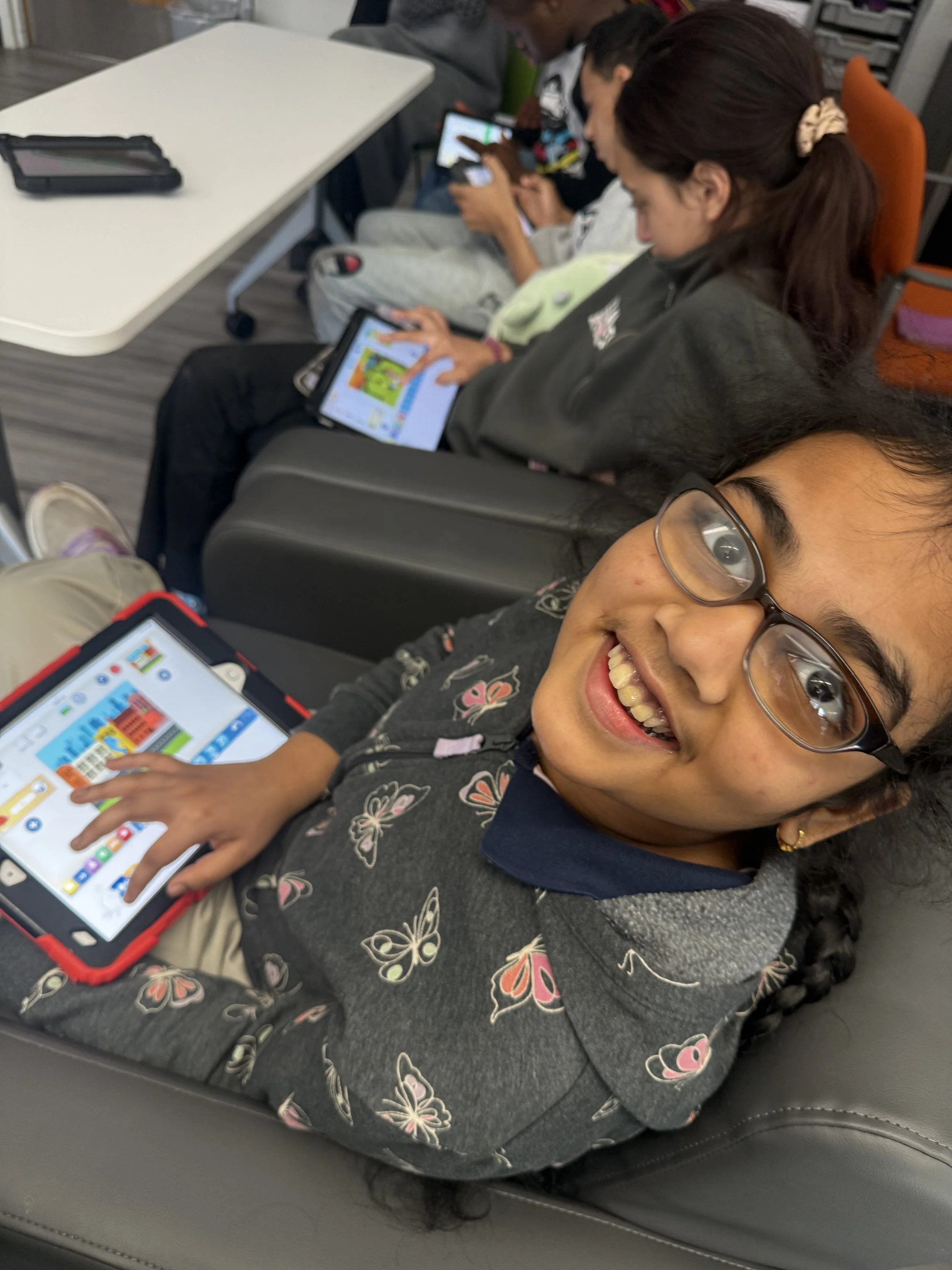 A student smiles while working on a tablet