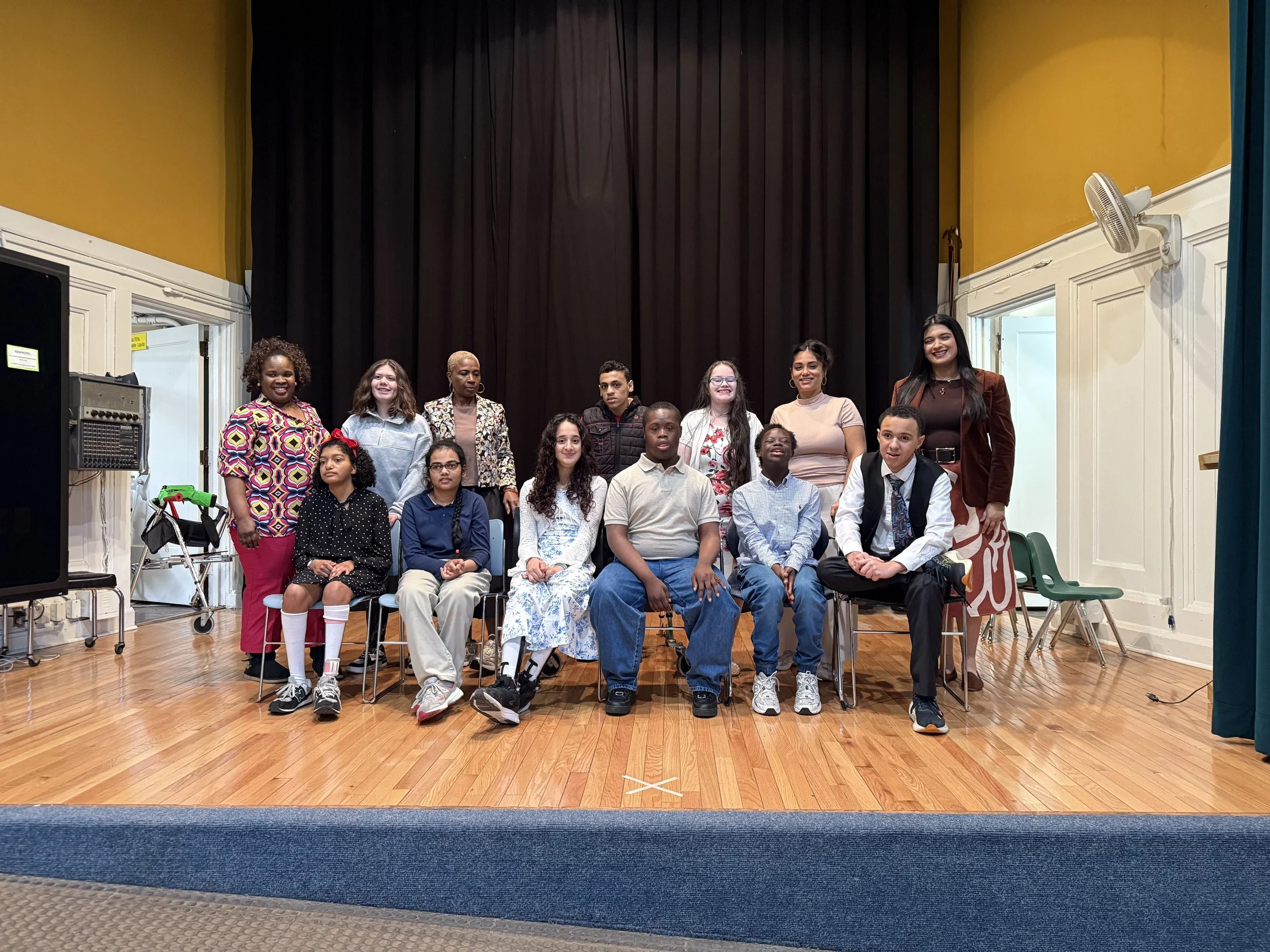A class gathers for a group photo on the auditorium stage