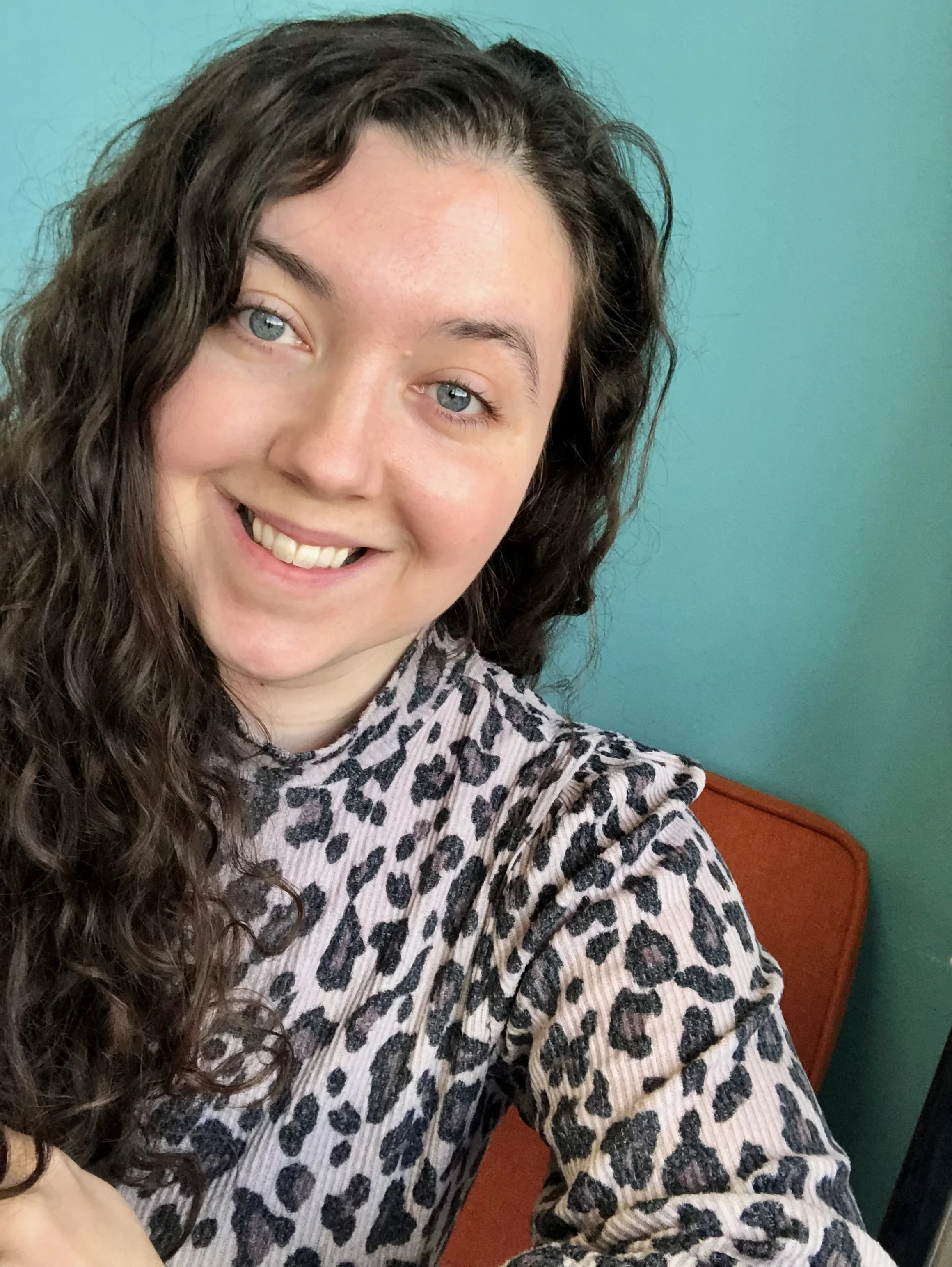 A person dressed in a gown playing the piano in a room with books and a window.