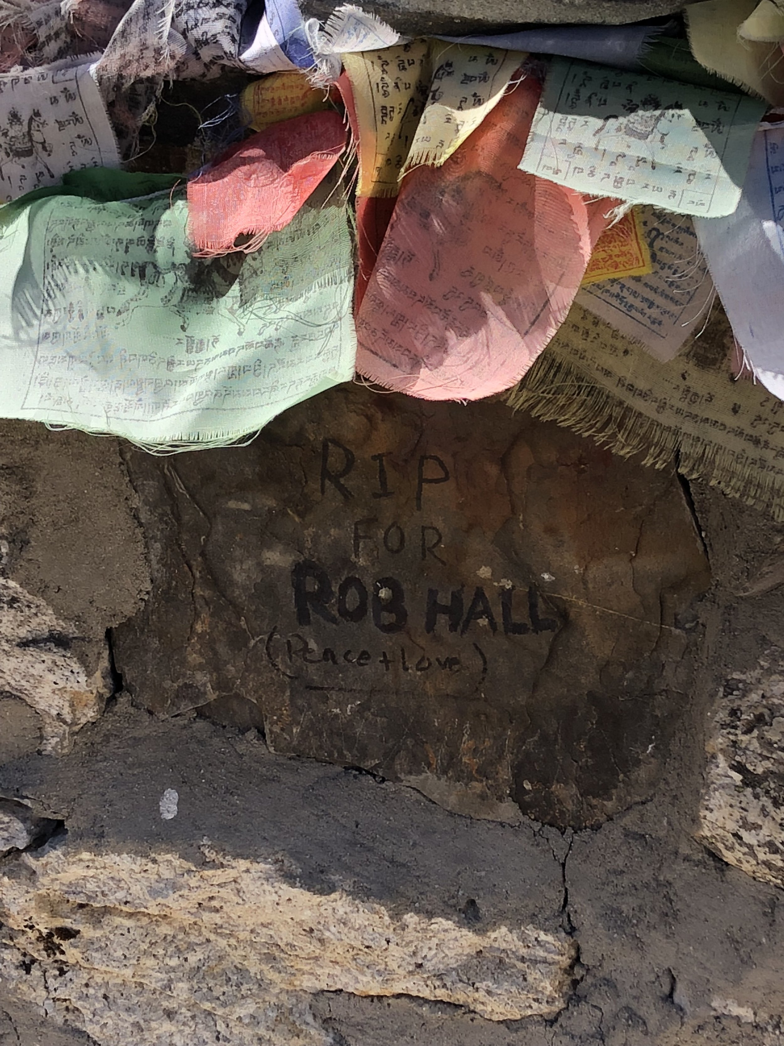 Memorial cairn for Rob Hall at Thukla Pass in Nepal, surrounded by prayer flags, honoring the Adventure Consultants guide who died during the 1996 Mount Everest disaster.