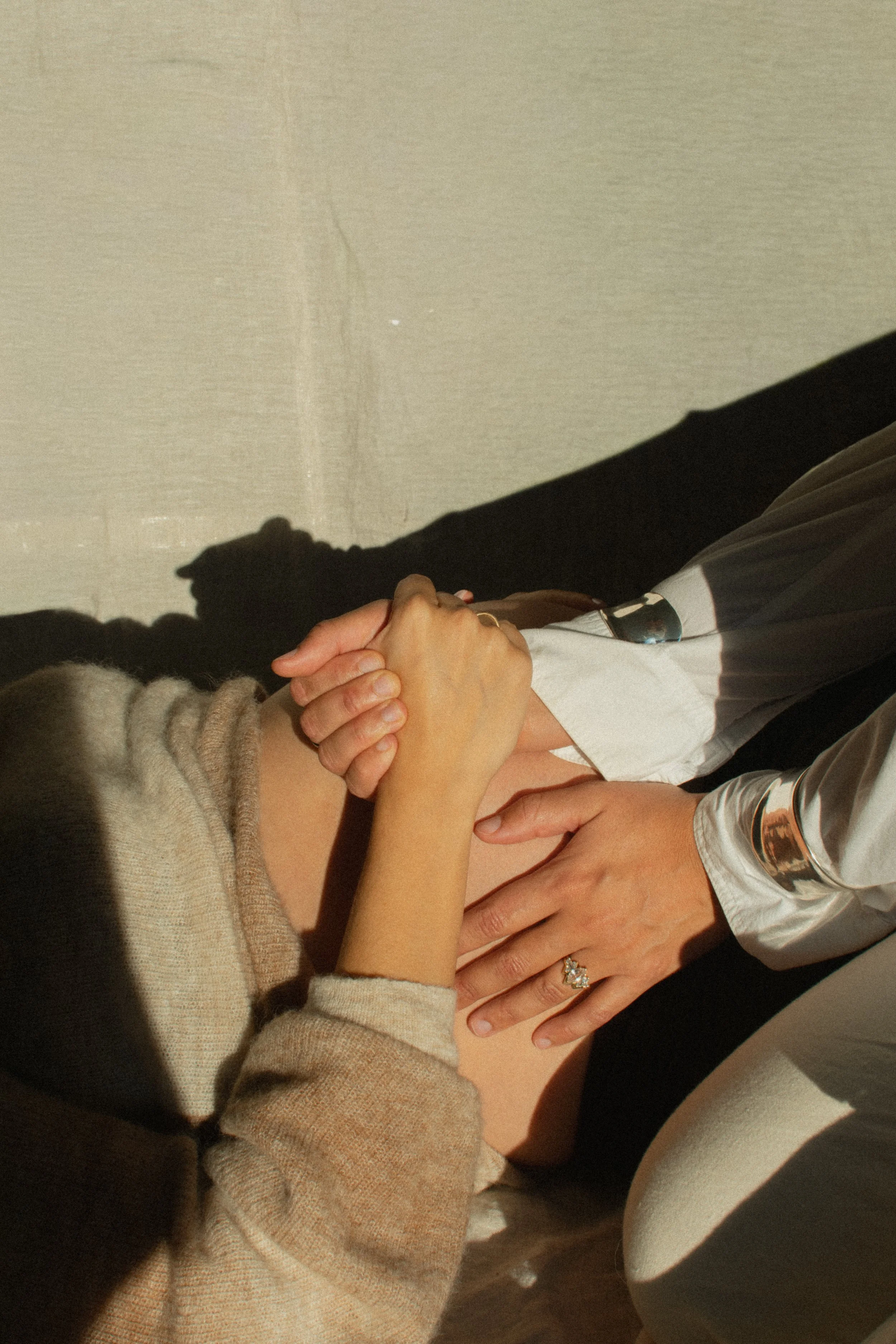image of a pregnant person holding the hand of a support person in the sunlight