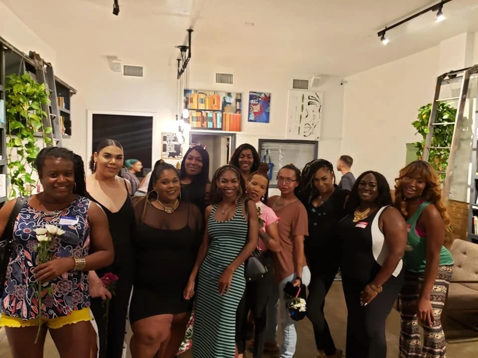 Group of women gathered indoors at a social event, smiling and posing for a photo.