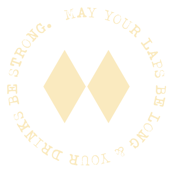 Circular design with two beige diamonds in the center; phrase around the circle reads, 'May your Laps be long & your Days be strong,' in cream-colored text on a black background.