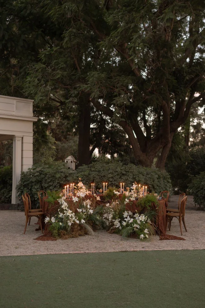 Elegant and romantic table set up in garden with flowers, garland and candles for an intimate photoshoot for a local brand.