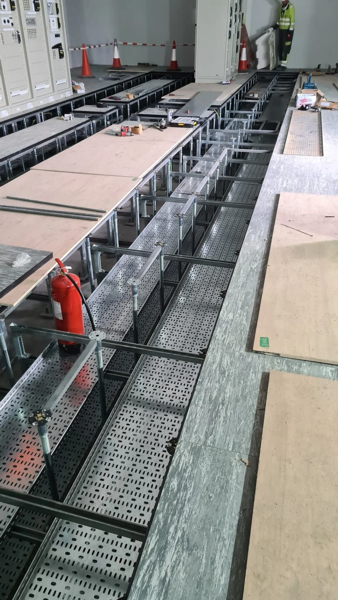 Construction workers installing metallic framework and wooden panels at a construction site.