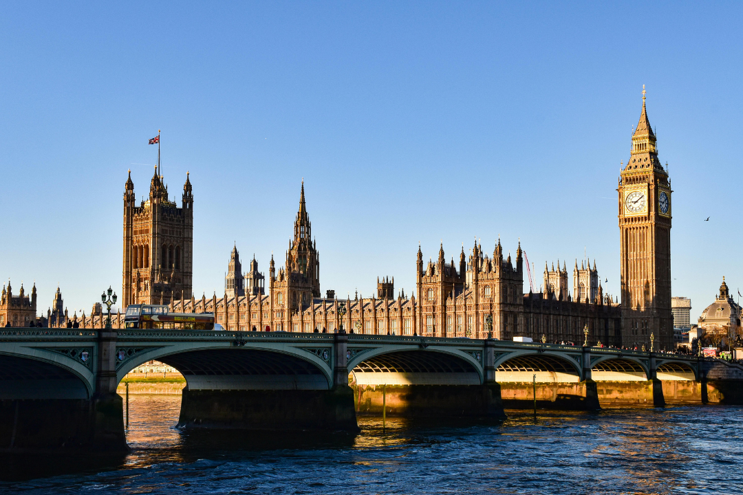View of the Palace of Westminster with Big Ben clock tower in London, UK, during the day with clear skies.