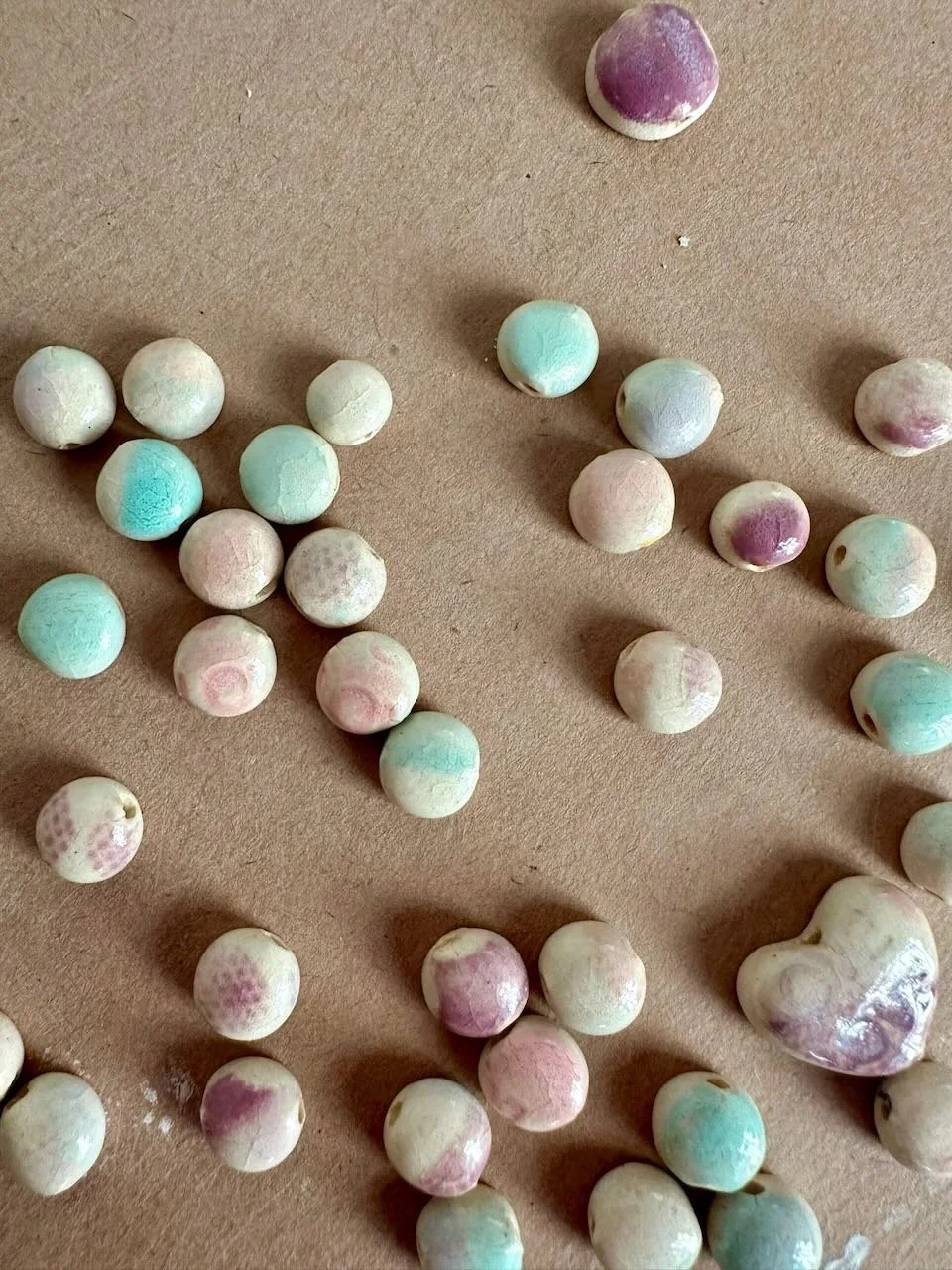 Colorful candies scattered on a brown surface, some with pastel shades of pink, blue, and purple.