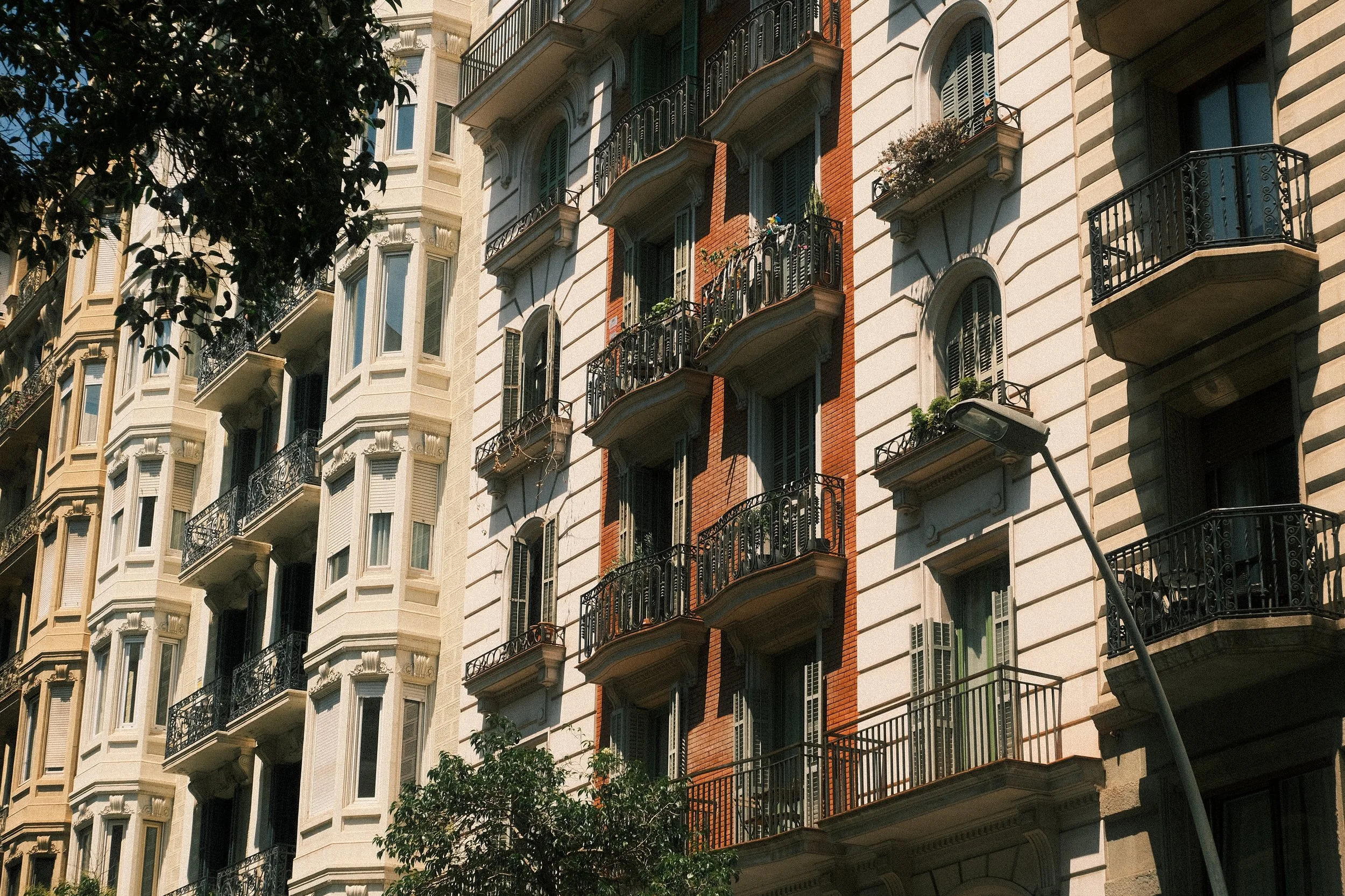 Multiple residential buildings with balconies and decorative facades, with a streetlamp in the foreground.