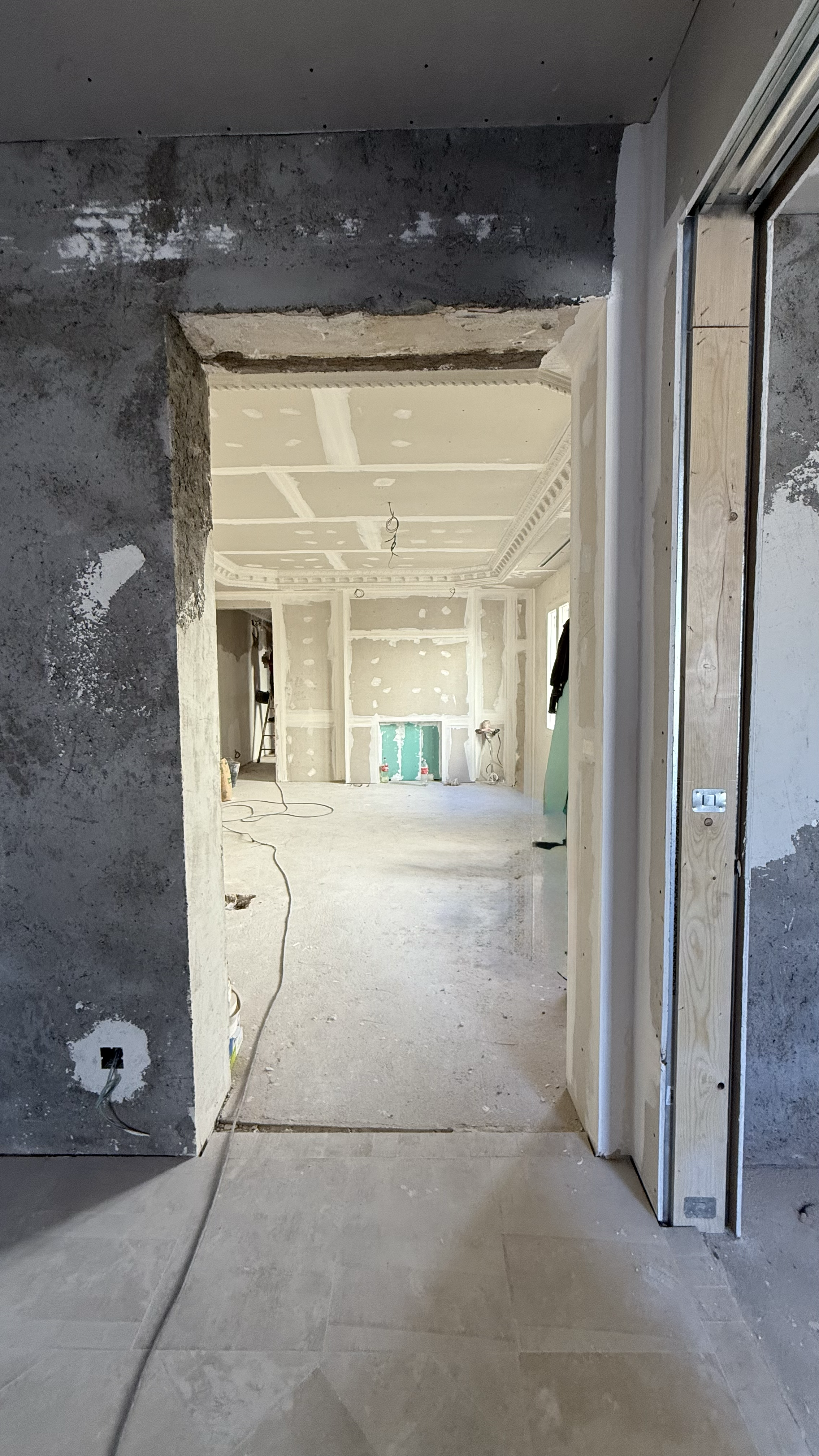 Interior of a house under construction with unfinished drywall, exposed wiring, and new flooring.