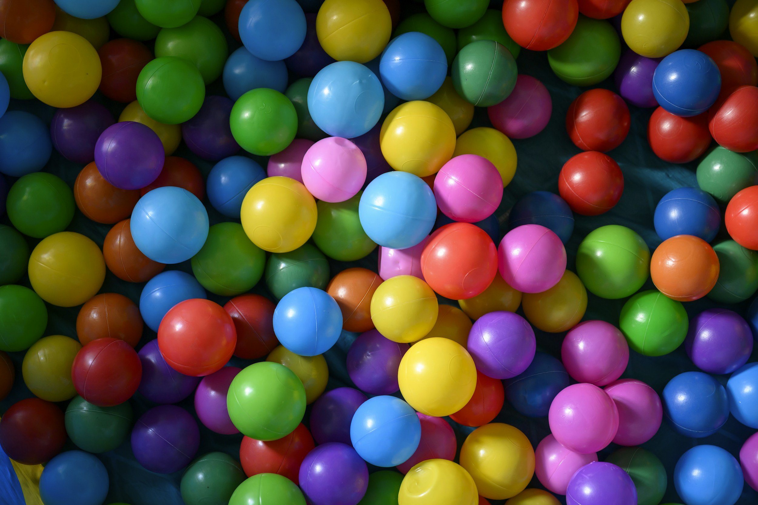 A colorful assortment of plastic balls, including yellow, blue, purple, green, pink, red, and orange, piled together.