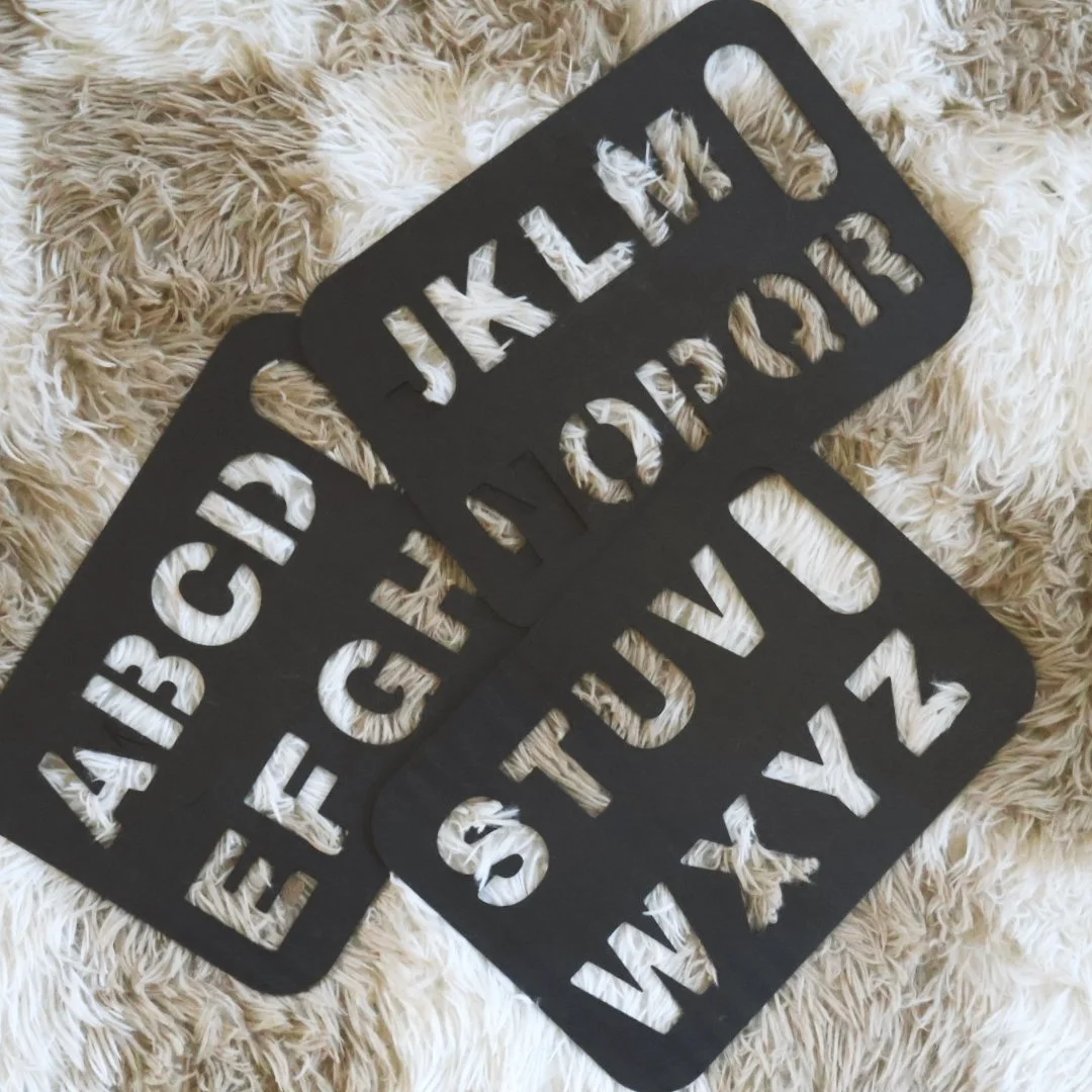 Black stencil letter boards placed on a beige shaggy surface.
