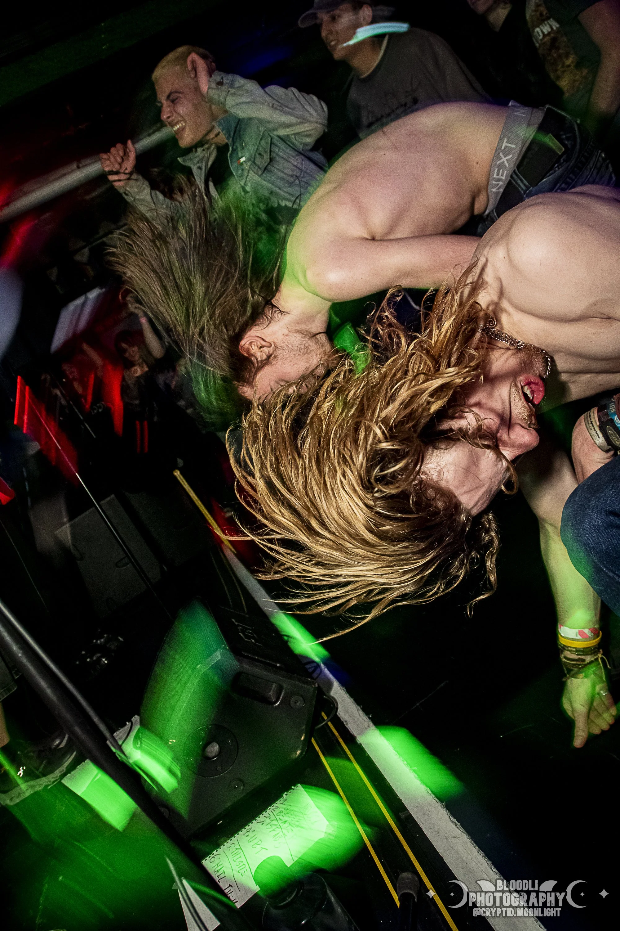 People dancing and enjoying a lively party with green laser lights in a dark room.