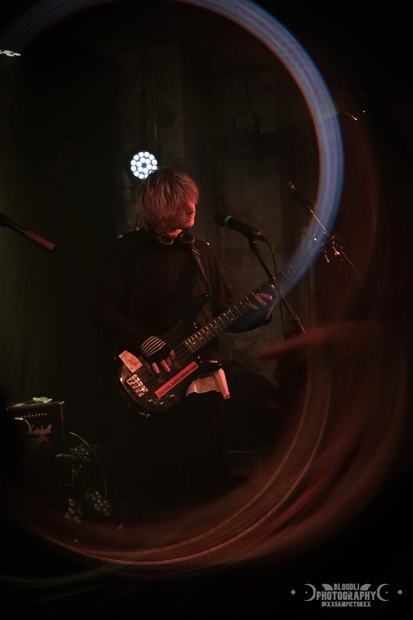 A musician playing an electric guitar on stage, with colorful light streaks and stage lights in the background.