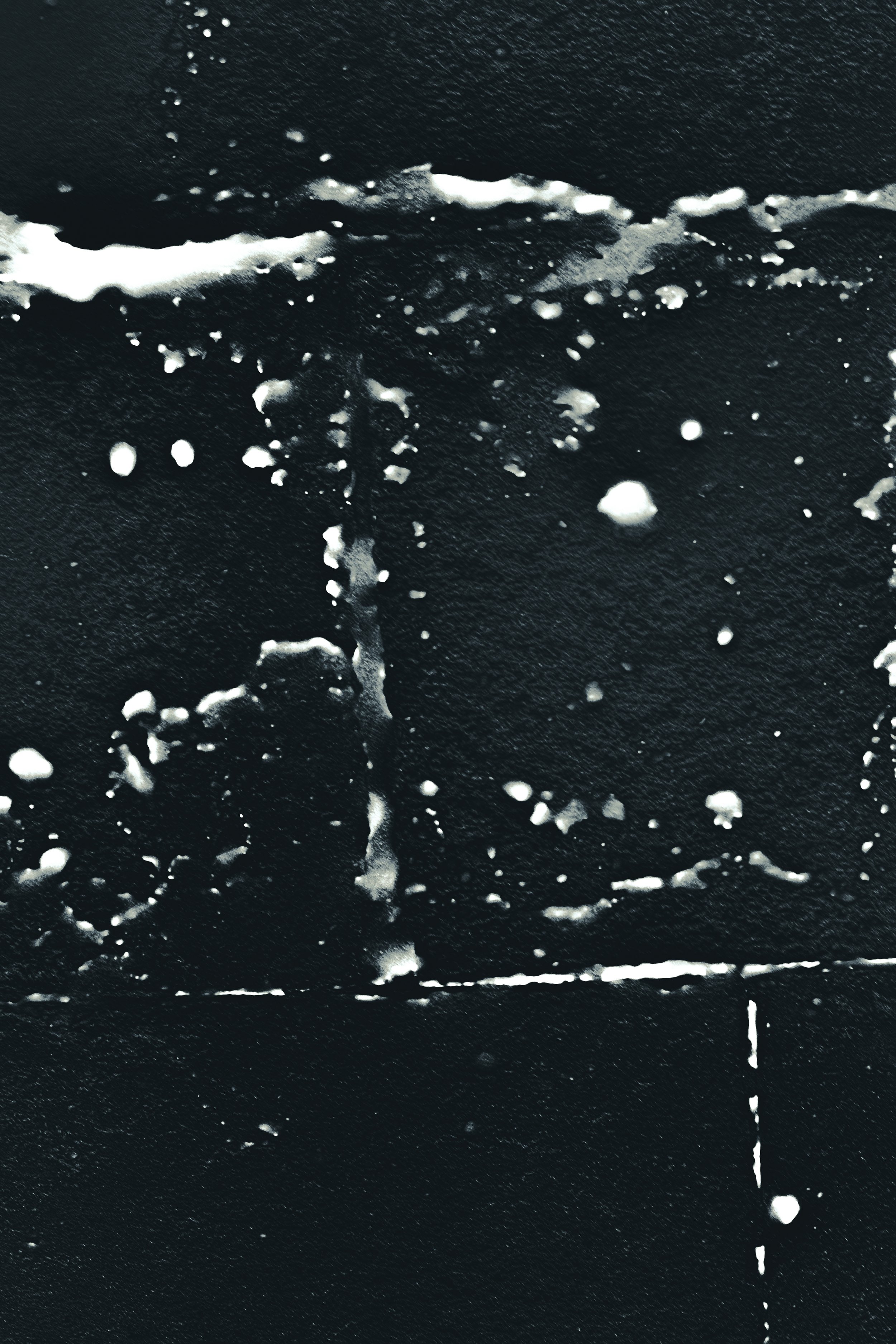 Abstract black and white splatter pattern with streaks and dots.