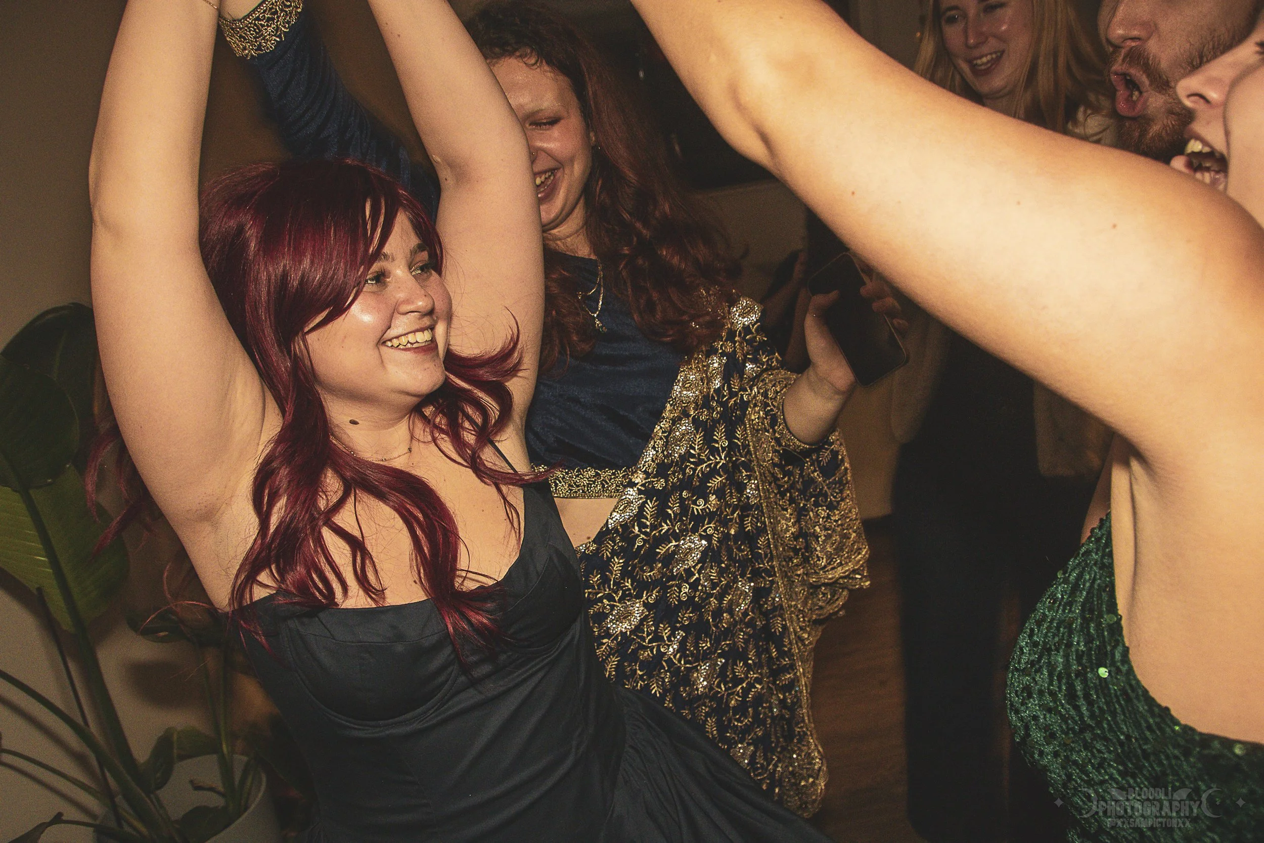Group of friends dancing and celebrating at a party, smiling and enjoying themselves.