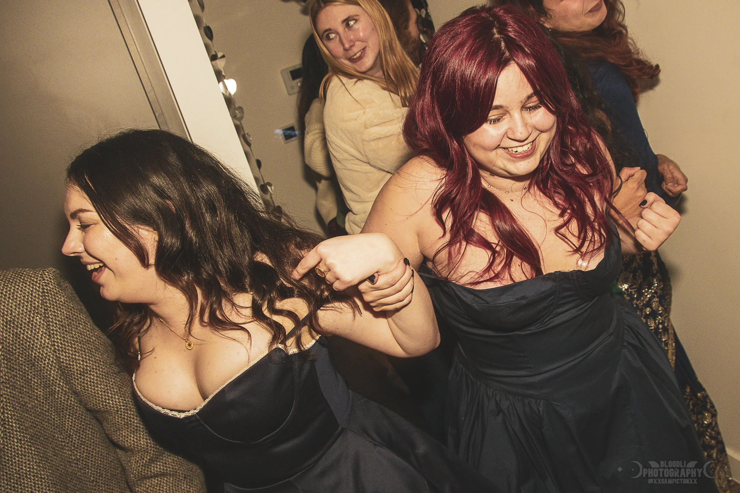 Group of women at a party playing a game of tug of war, with one woman pulling on another woman's hair as part of the game, all smiling and enjoying.