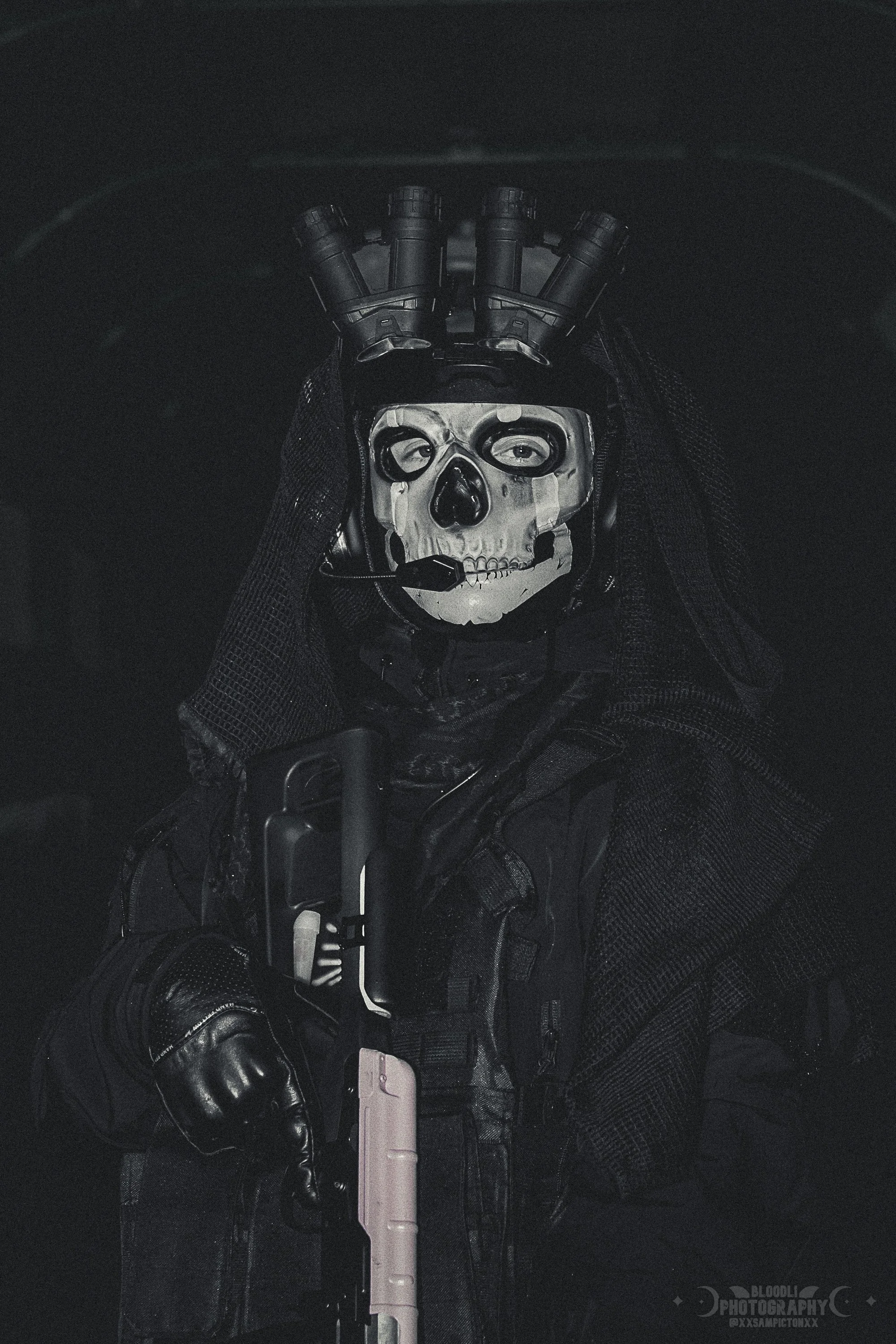 Person dressed in tactical black gear with a skull mask, holding a firearm
