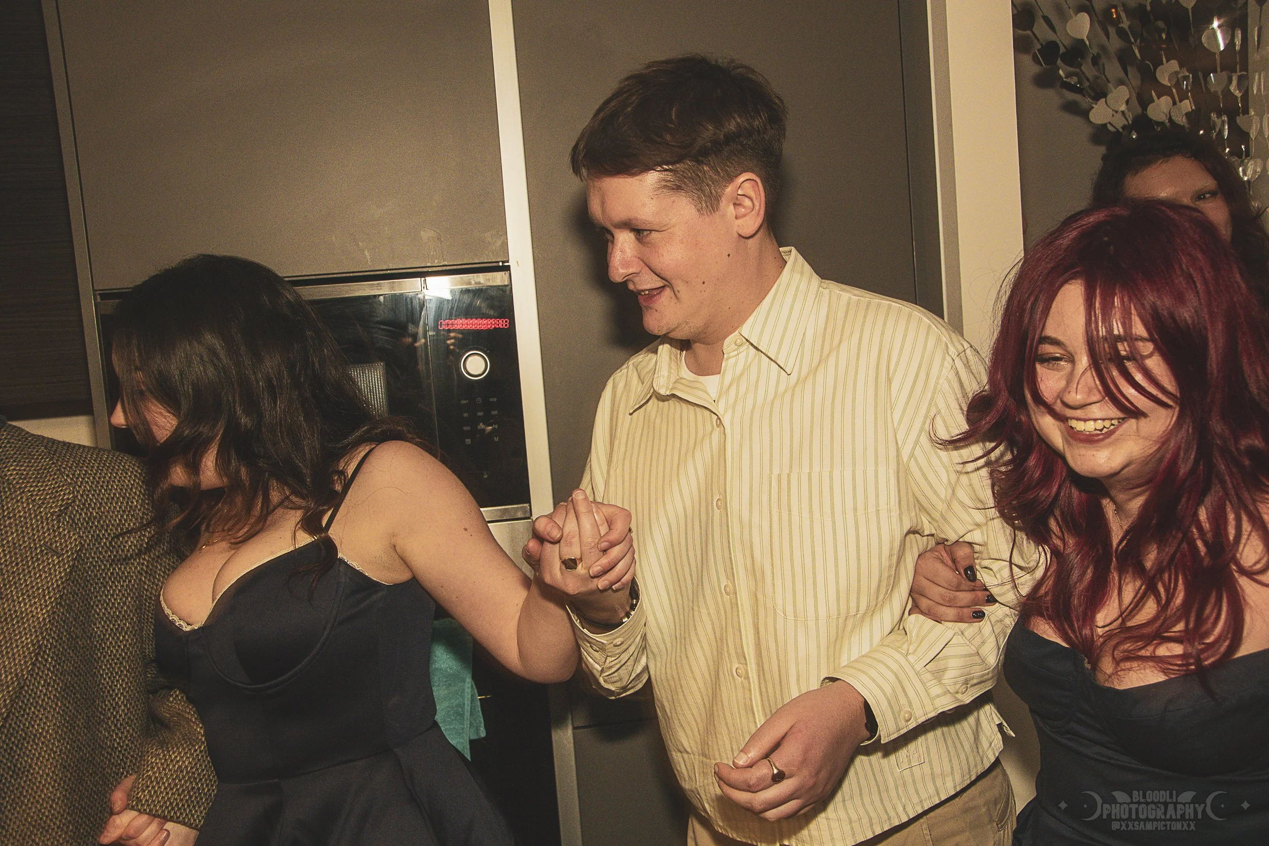 People dancing and holding hands at a party, smiling and enjoying themselves.
