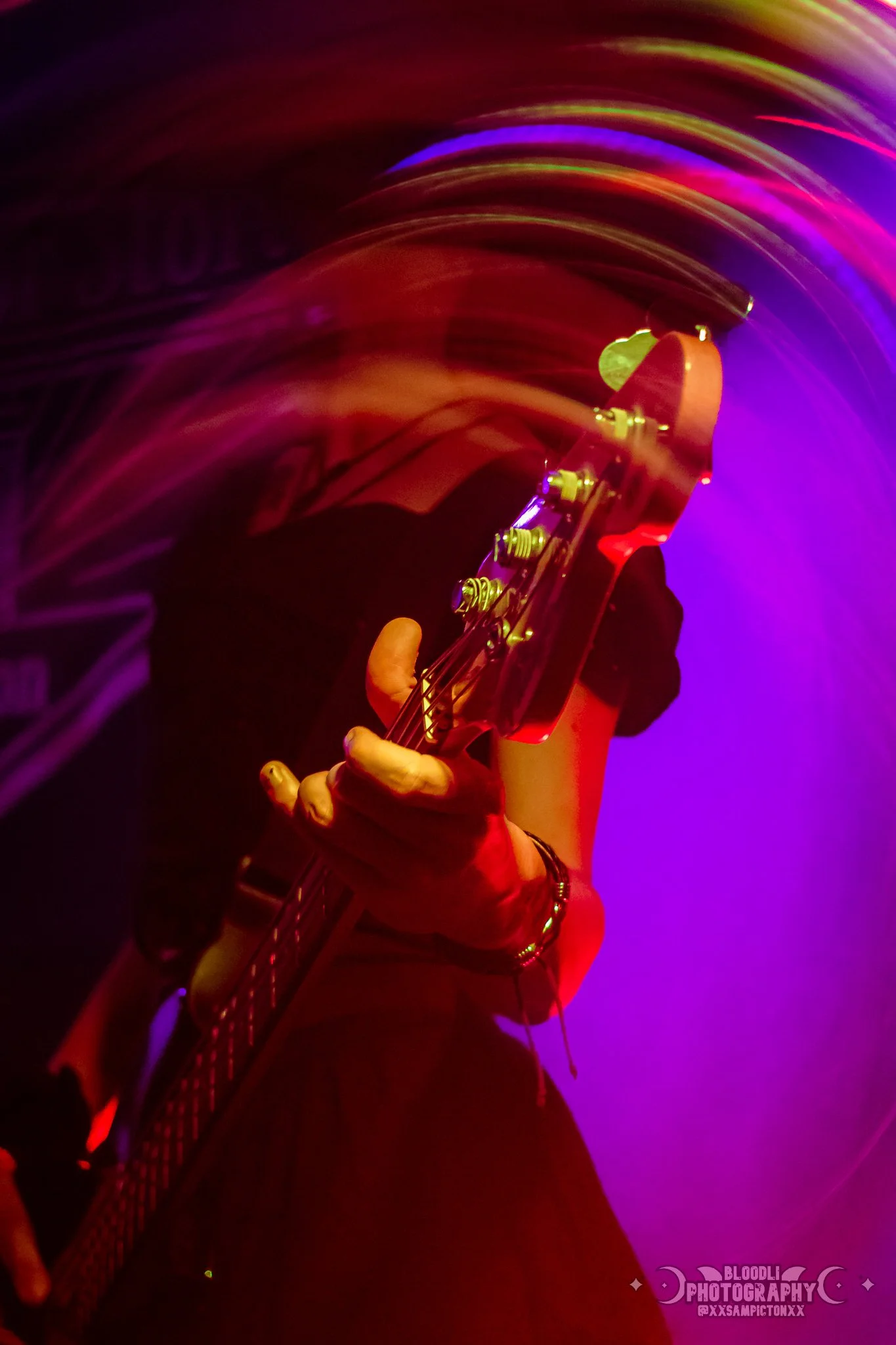 A person playing an electric guitar amidst vibrant, swirling multicolored lights, with a dark background and dynamic motion blur.
