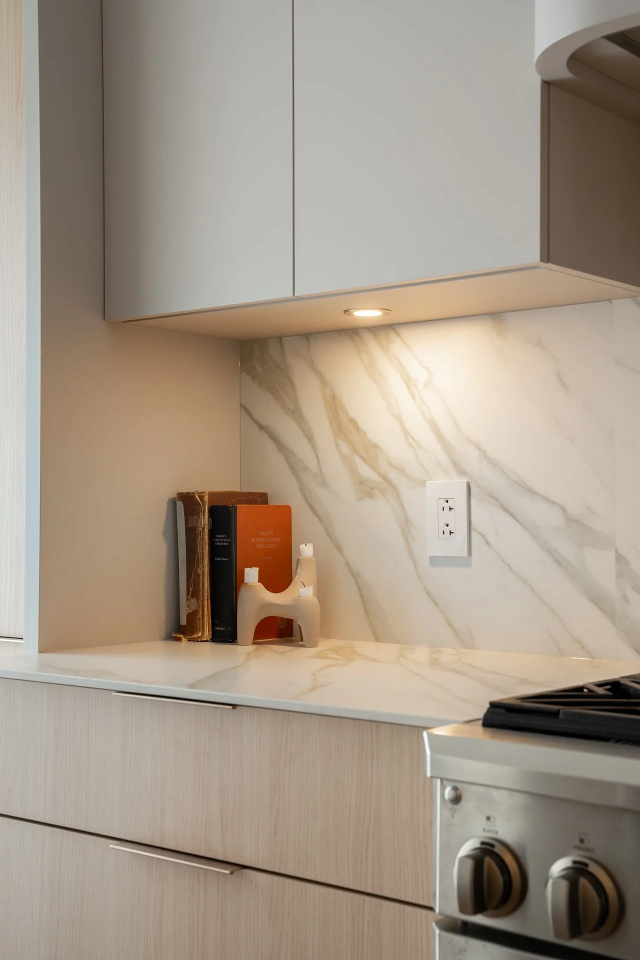 Cuisine moderne avec un comptoir en marbre, quelques livres, une sculpture en céramique et une prise électrique sur le mur.