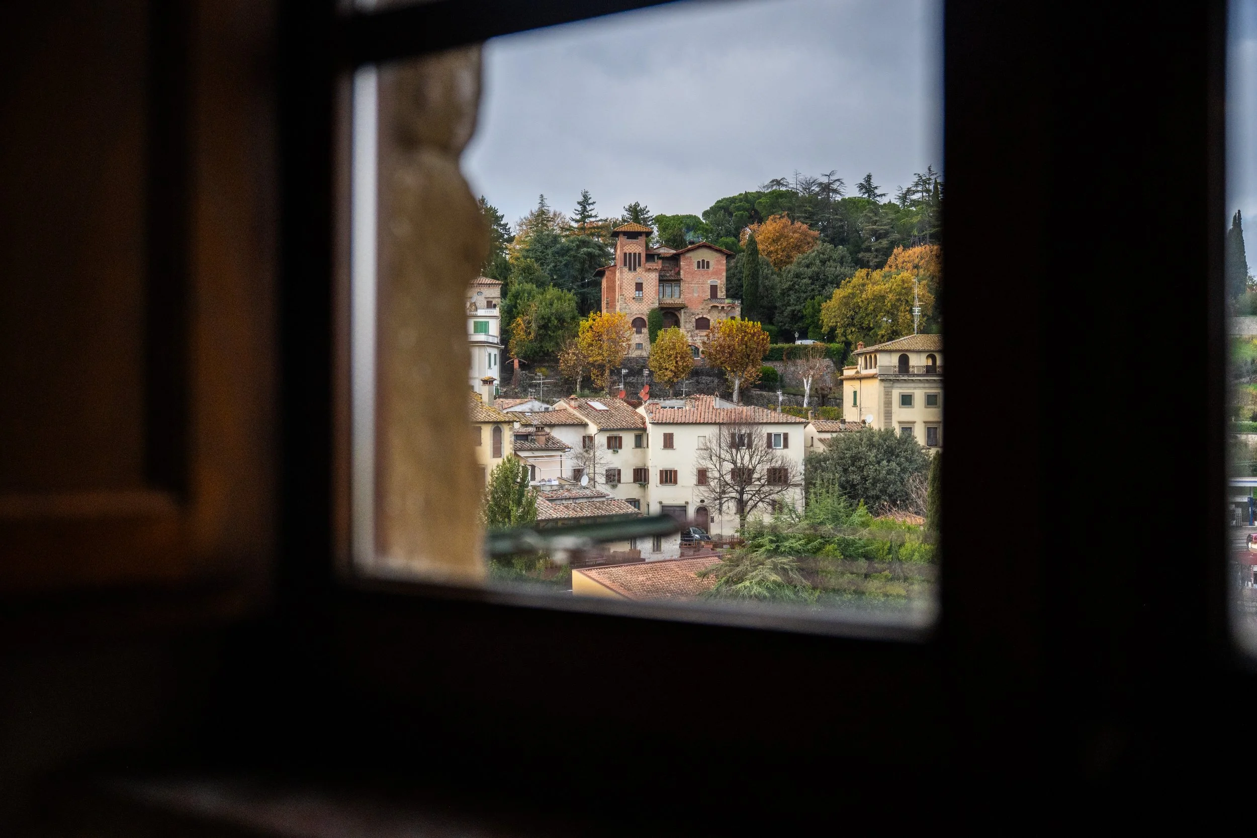 Vista di un paesaggio cittadino con case e alberi attraverso una finestra.