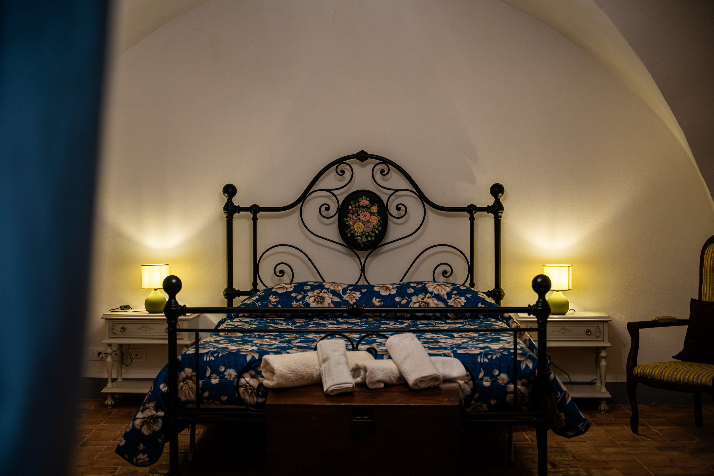 Letto con coperte e asciugamani in una stanza con pareti bianche e luci da comodino.