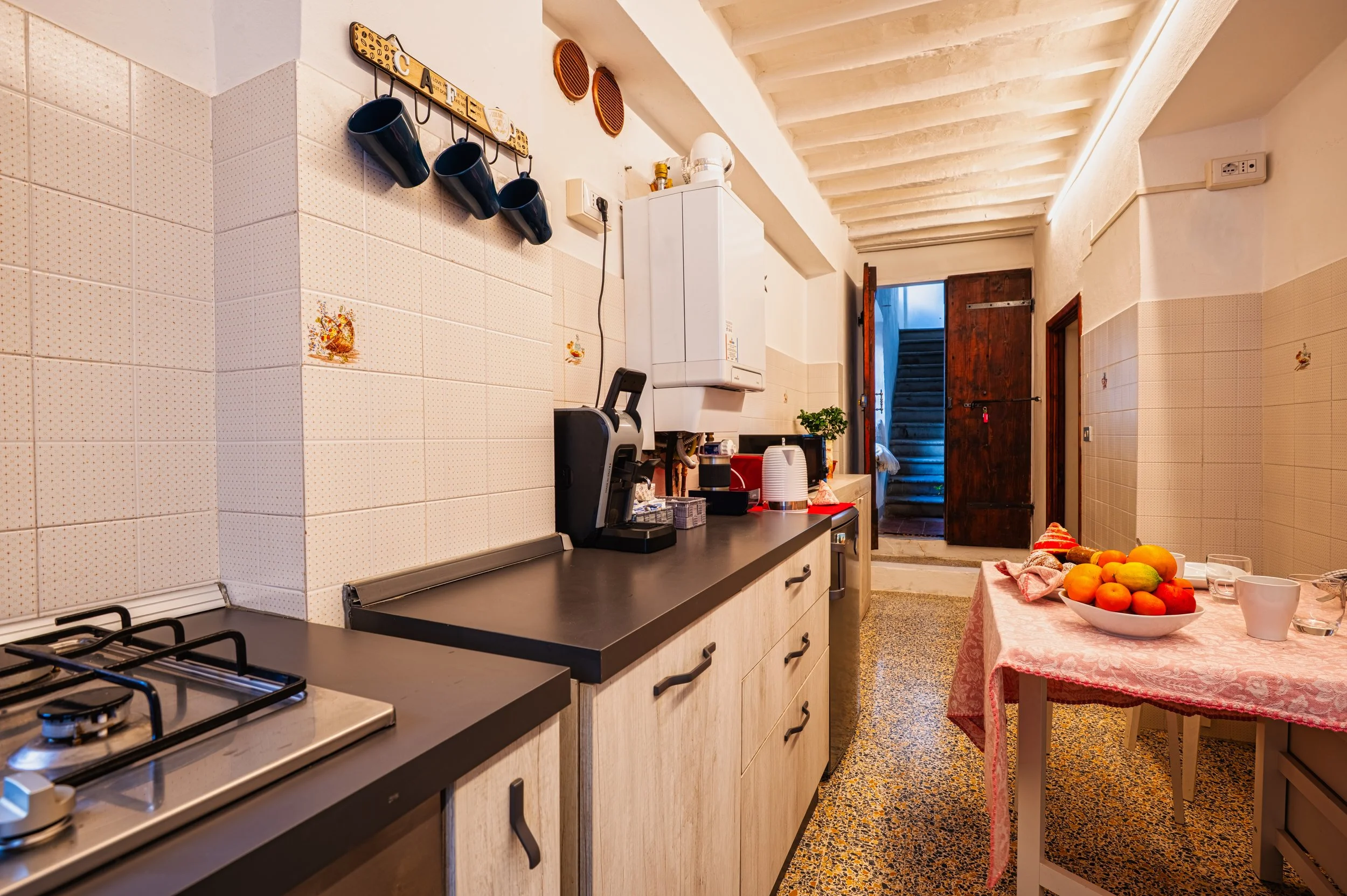 Cucina con tavolo, frutta e porta aperta, stile rustico e accogliente.