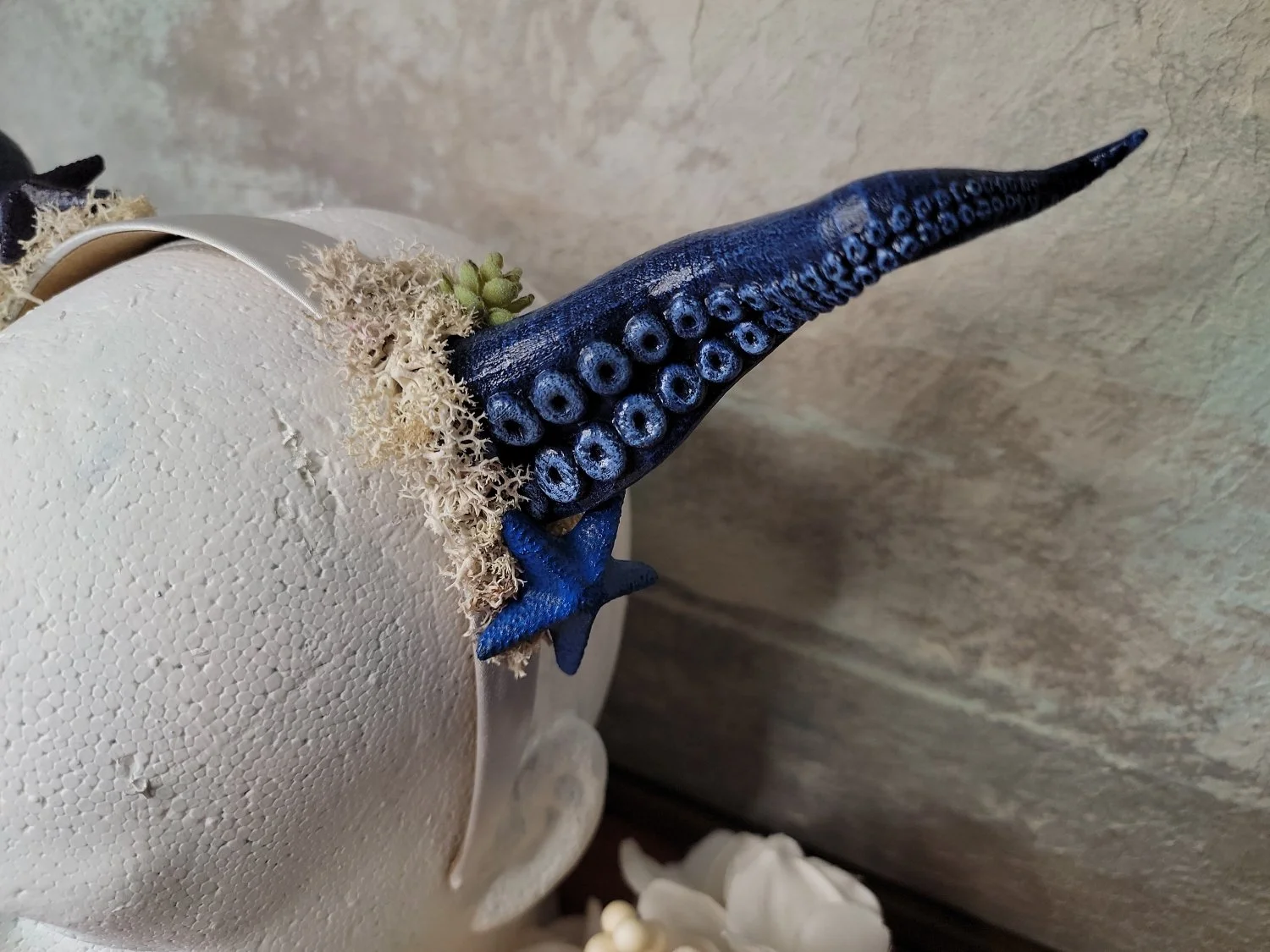 close-up of blue tentacle horn with a matching blue starfish, white moss, and plant-like accents