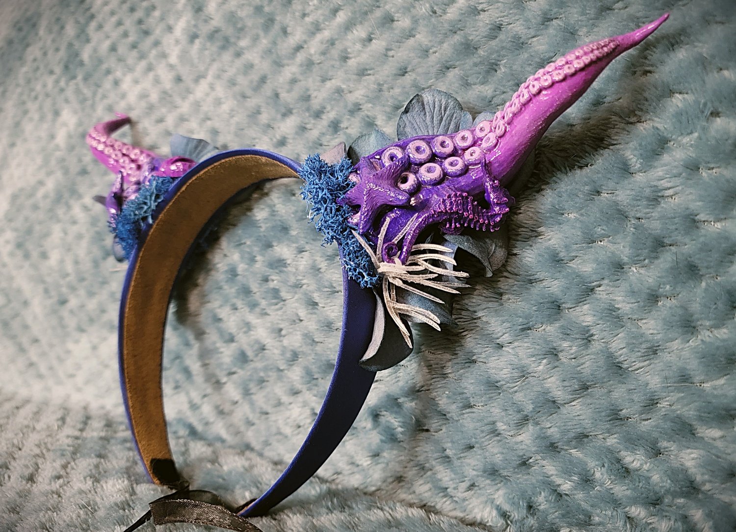 Ombre purple tentacle horn, mounted on a blue headband, with matching starfish and seahorse accents, as well as ocean-themed florals surrounding the base
