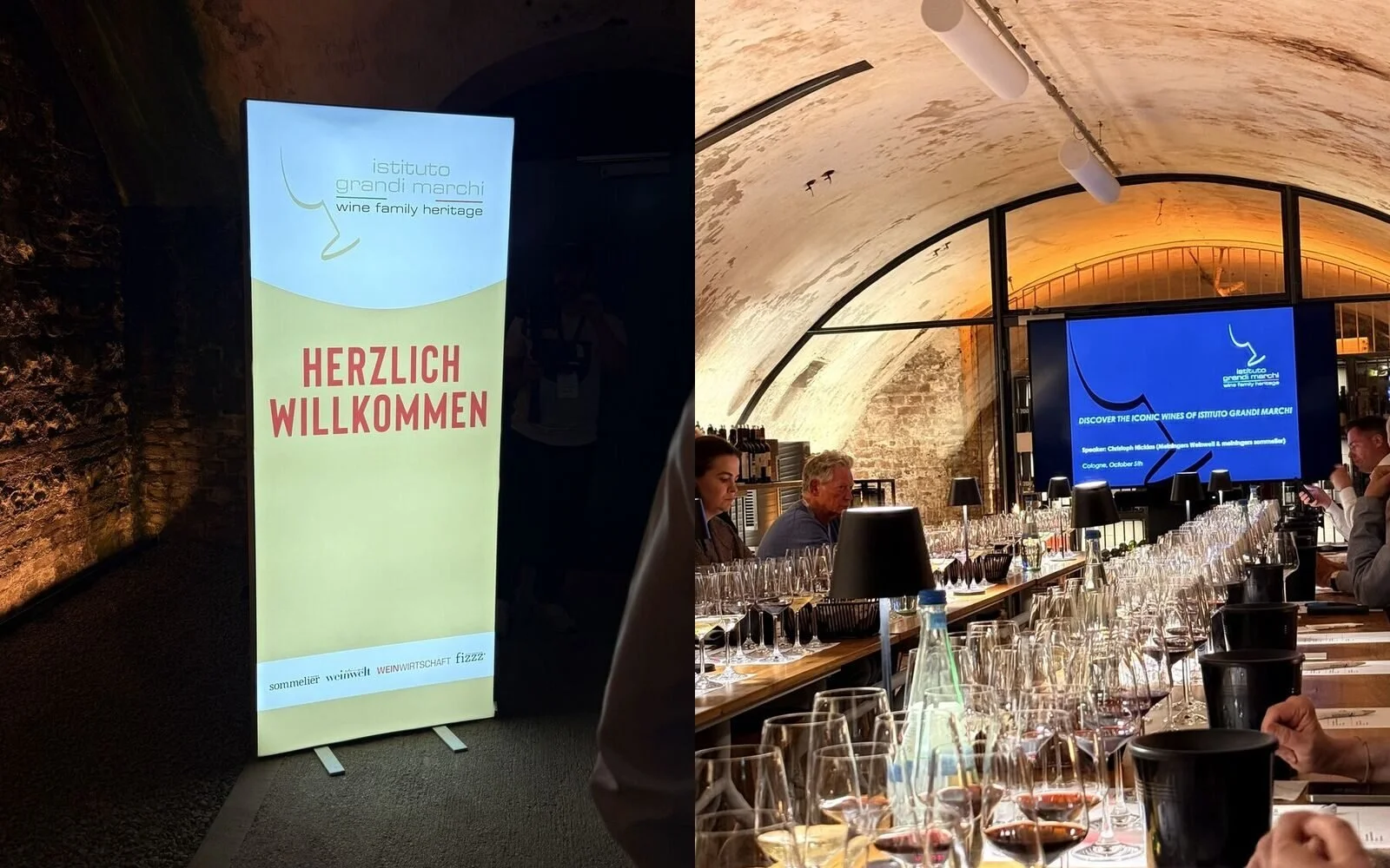 Welcome sign of the Istituto Grandi Marchi masterclass in Cologne next to the vaulted stone cellar of wineBANK Köln, set up with a long tasting table and presentation screen