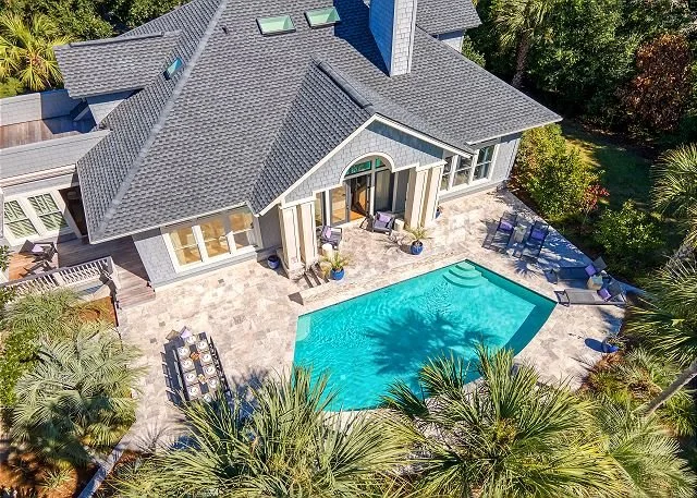 Aerial view of 108 Goldeneye Drive, a vacation house with a backyard swimming pool, surrounded by trees and outdoor seating areas.