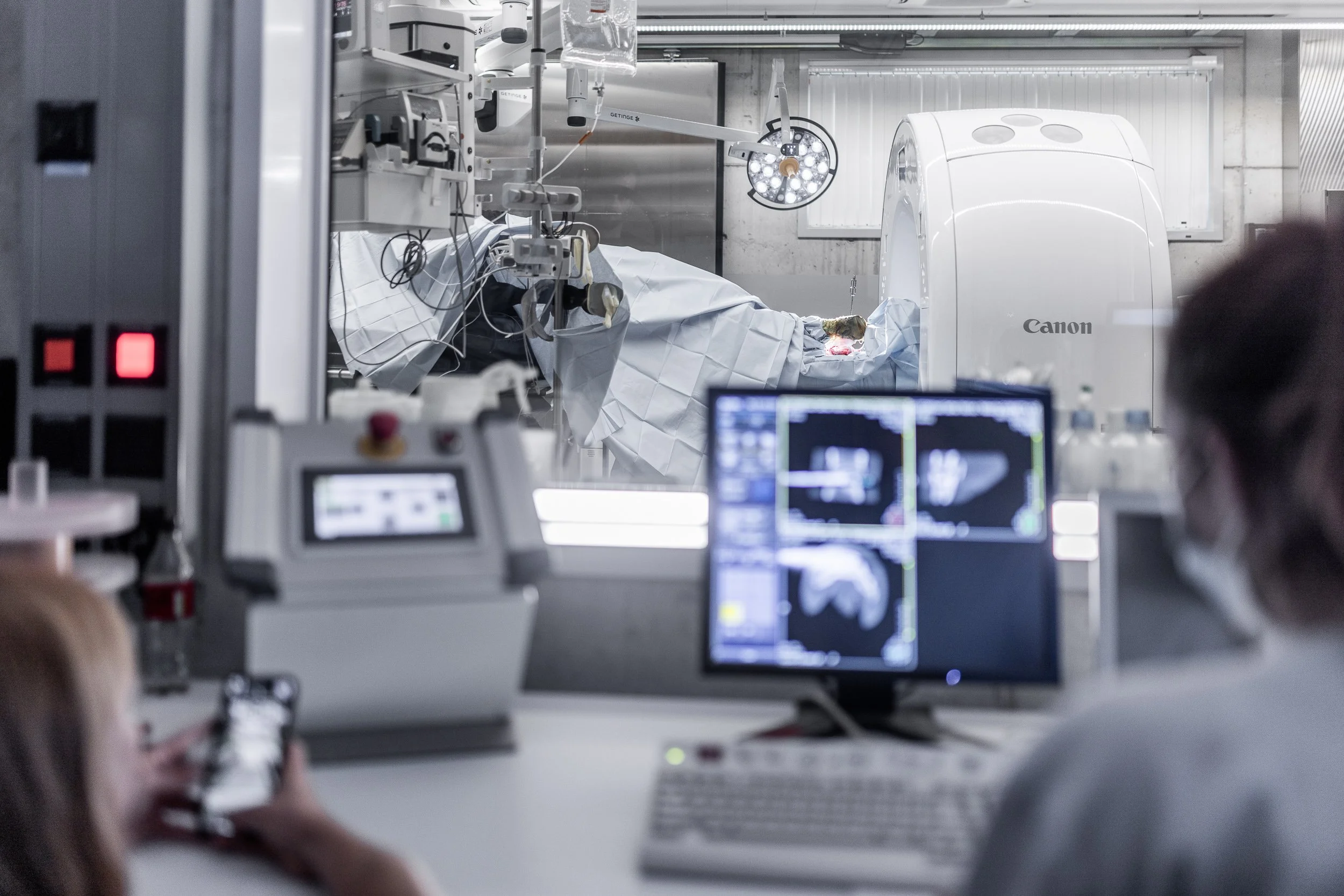 Medical professionals monitoring a patient undergoing a procedure in an MRI machine in a hospital or medical facility.