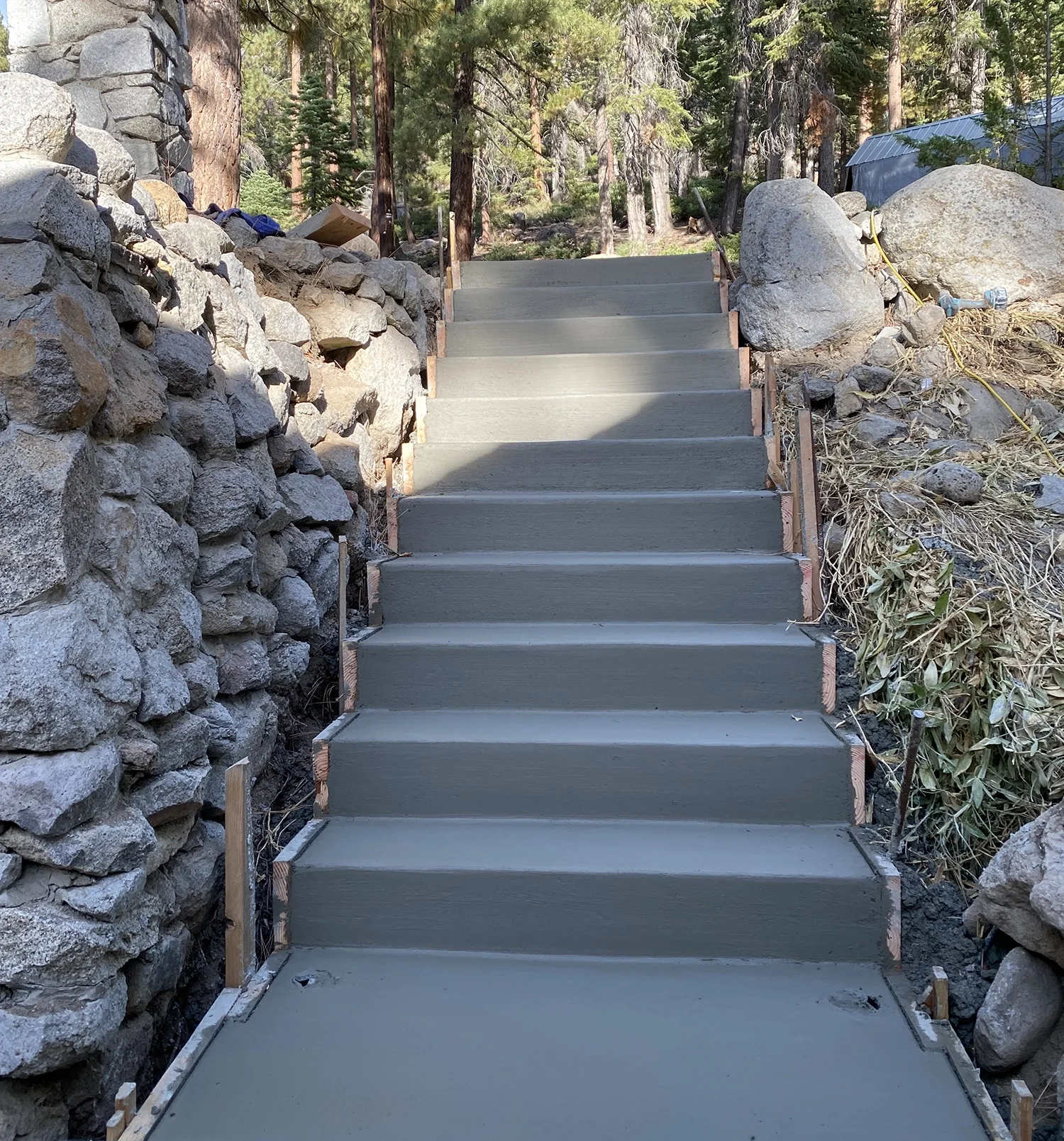 freshly poured concrete stairs with rock wall on one side
