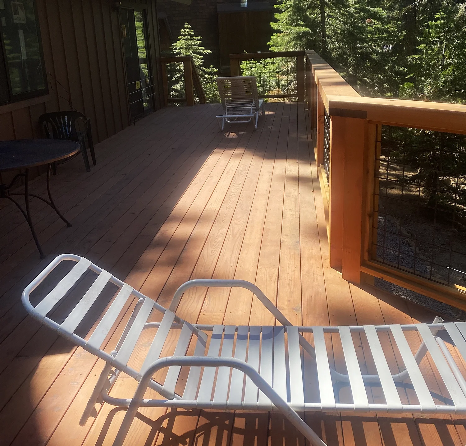home's back deck with armchair in wooded setting