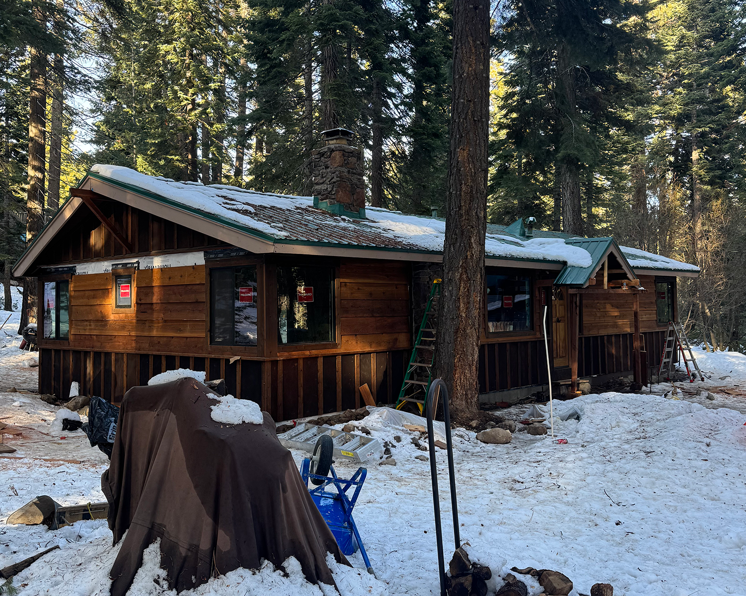 cabin in woods with new wood siding being applied during winter