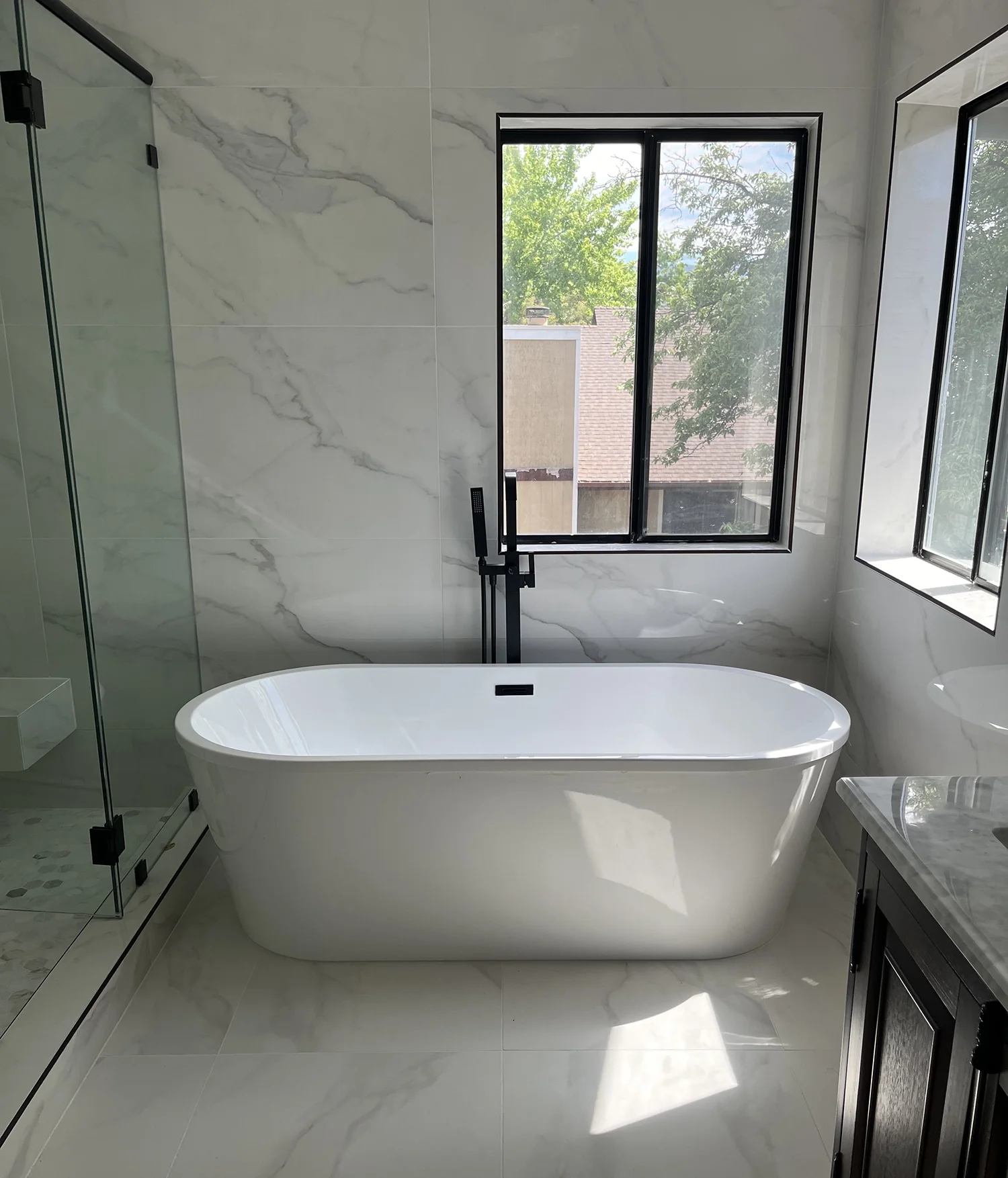 modern white porcelain bathtub in white marble bathroom