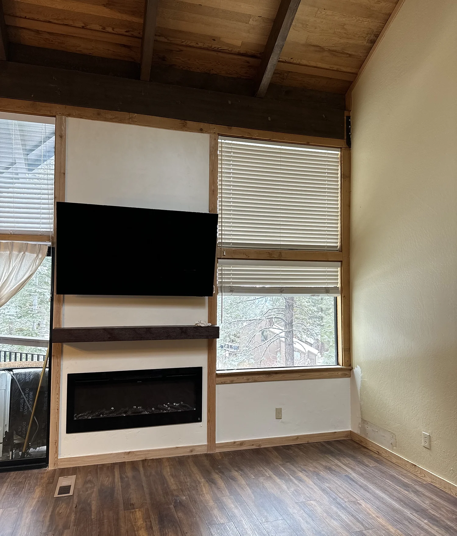 modern gas fireplace insert with flat screen tv and wood flooring surrounded by window