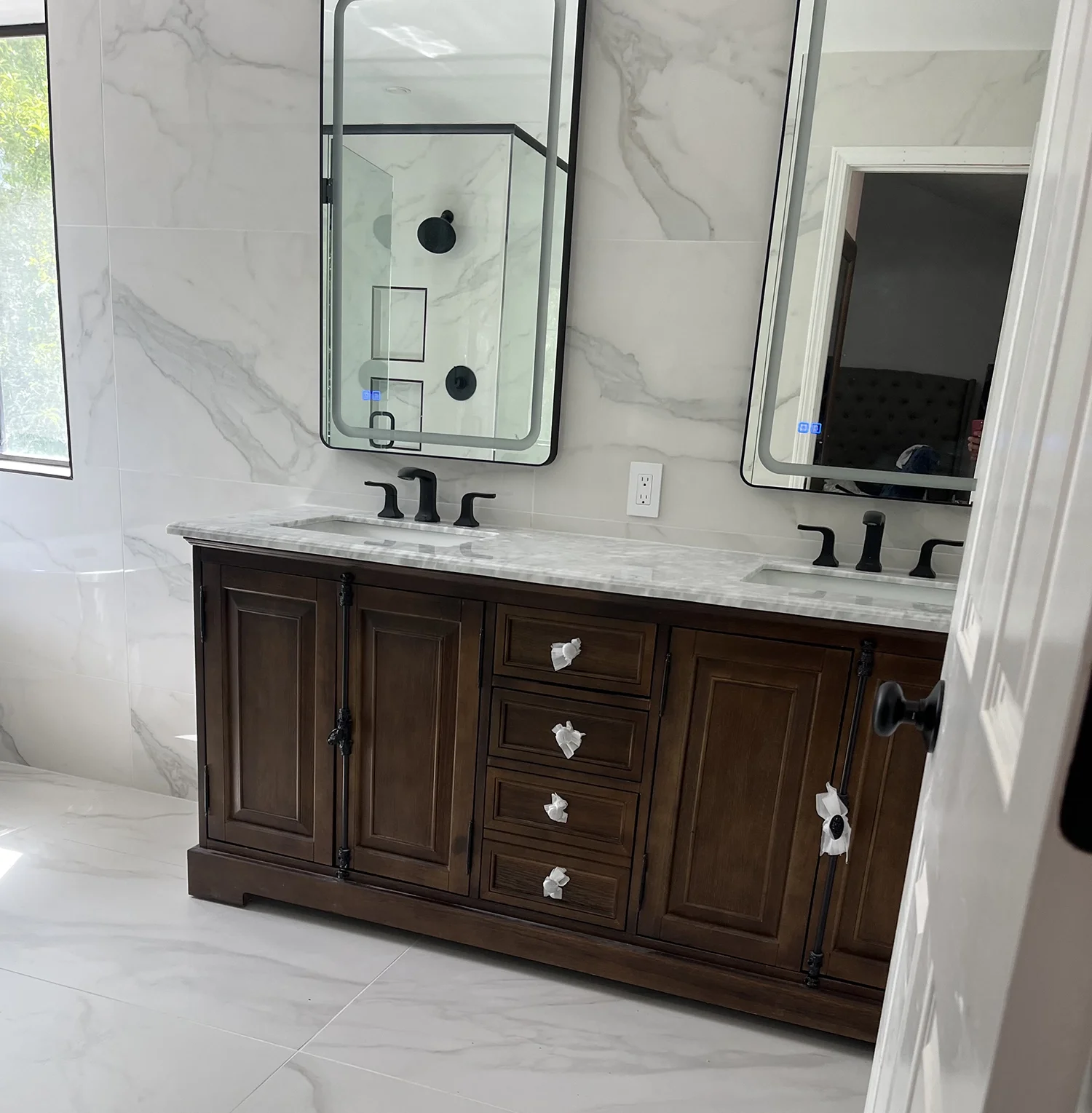 dark wood vanity in white marble bathroom with mirror