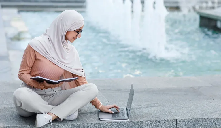 A learner studying outdoors with a laptop as part of a workplace learning campaign.