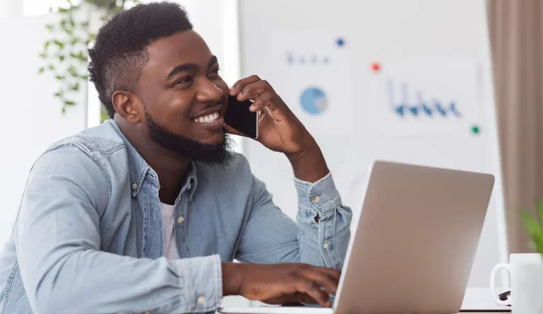 A professional using a laptop and phone while working through a business problem.