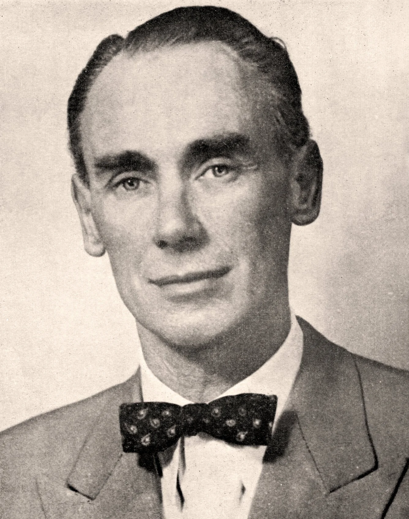A black-and-white portrait of a young man in a suit and bow tie, with neatly combed hair.
