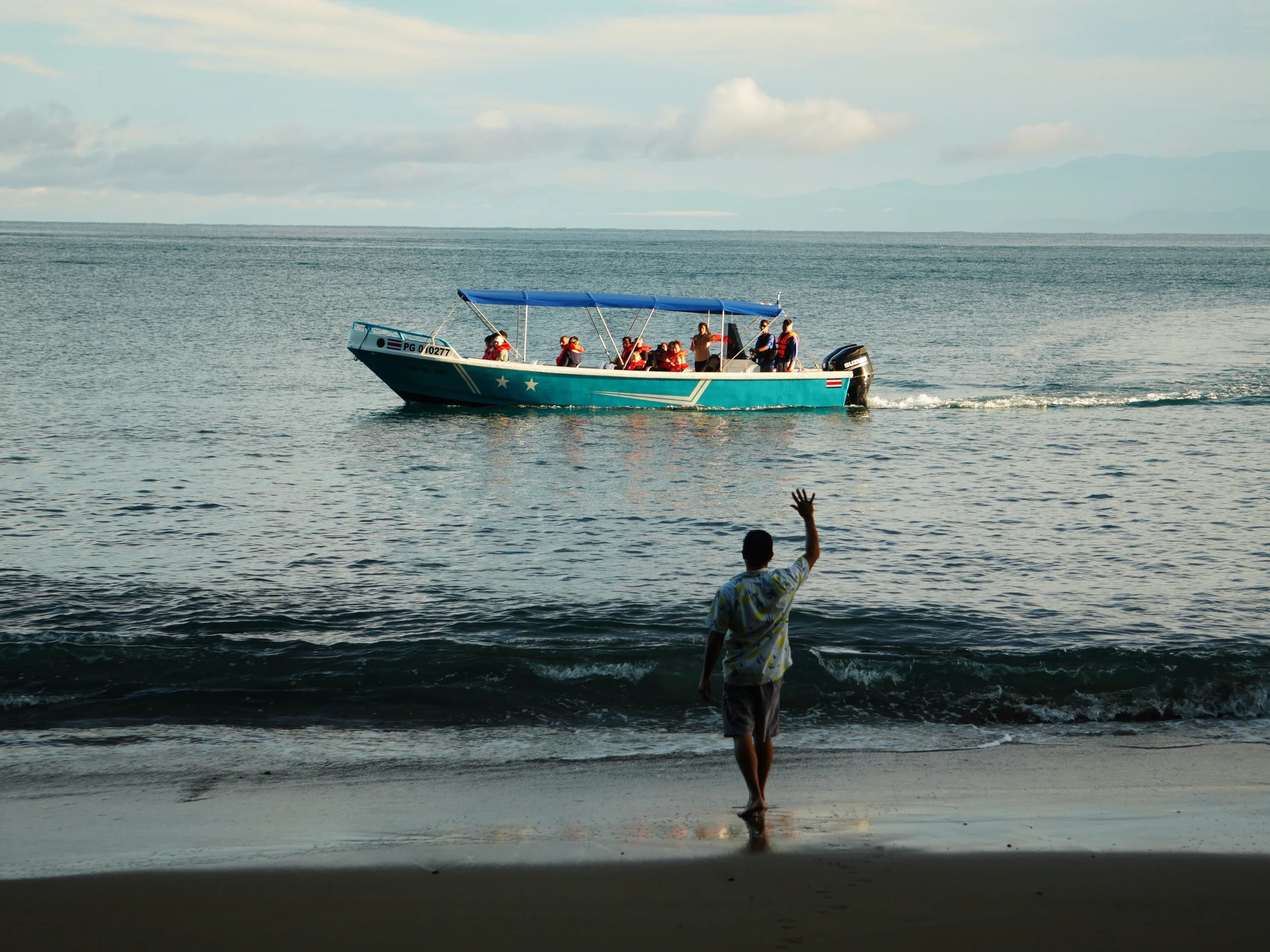Small boat arriving at the shore of the Osa Peninsula, Costa Rica, with a our host waving from the beach.