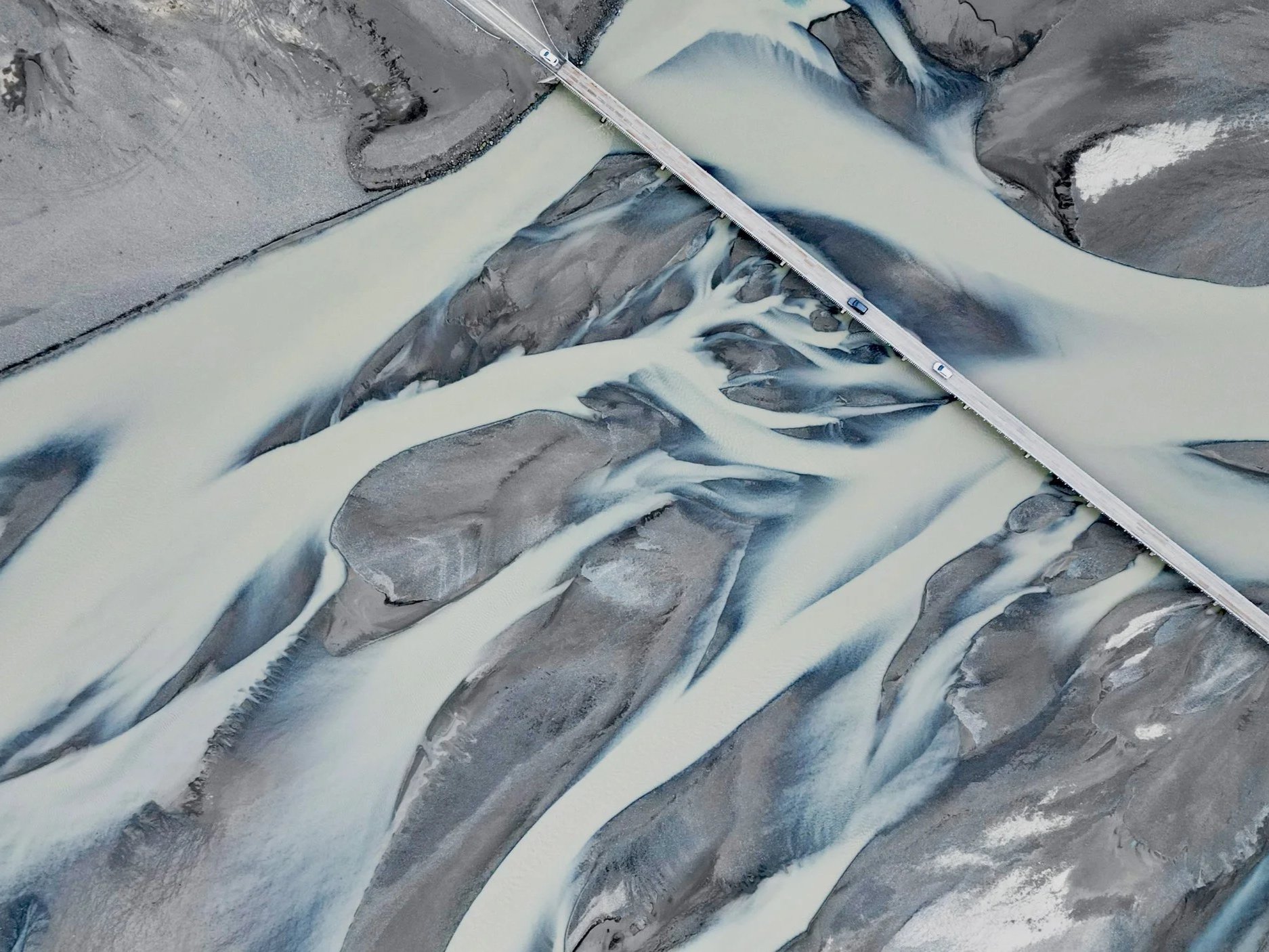 Aerial view of braided rivers and morning traffic on the Icelandic highway. Captured by a drone.